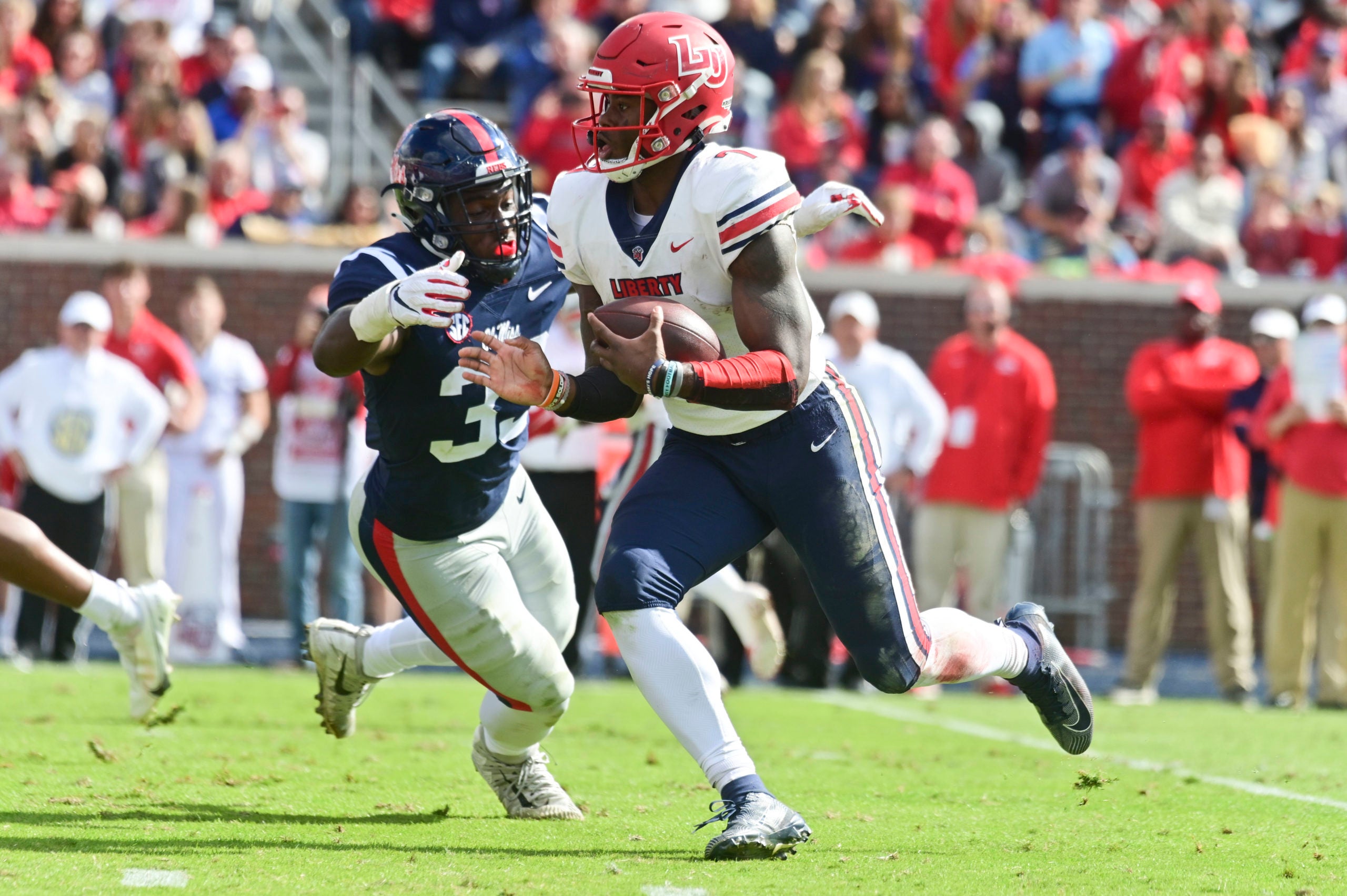 Nov 6, 2021; Oxford, Mississippi, USA; Liberty Flames quarterback Malik Willis (7) runs the ball while defended by Mississippi Rebels linebacker Cedric Johnson (33) during the third quarter at Vaught-Hemingway Stadium. Mandatory Credit: Matt Bush-USA TODAY Sports