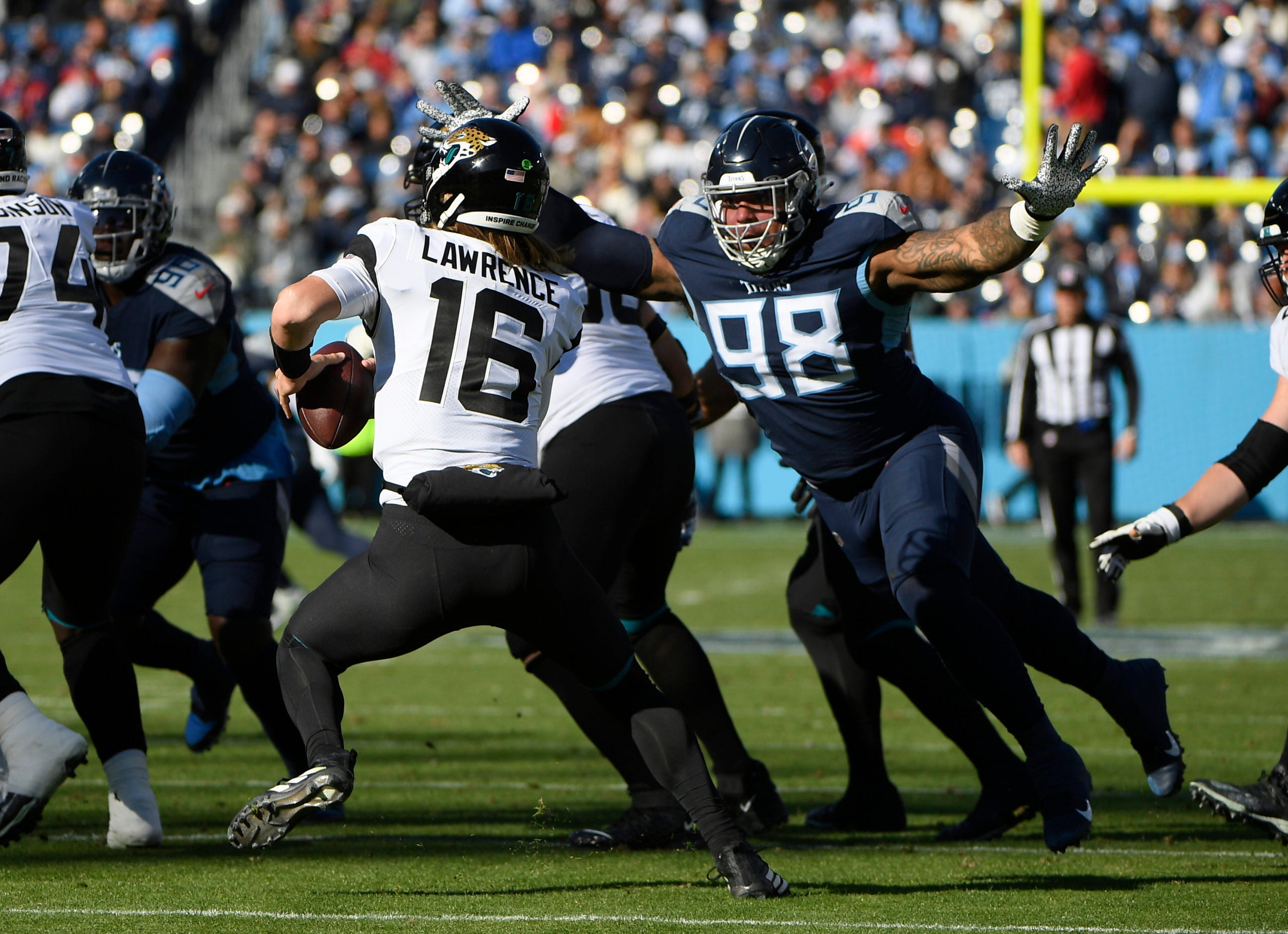 Dec 12, 2021; Nashville, Tennessee, USA;  Jacksonville Jaguars quarterback Trevor Lawrence (16) avoids the tackle of Tennessee Titans defensive tackle Jeffery Simmons (98) during the first half at Nissan Stadium. Mandatory Credit: Steve Roberts-USA TODAY Sports