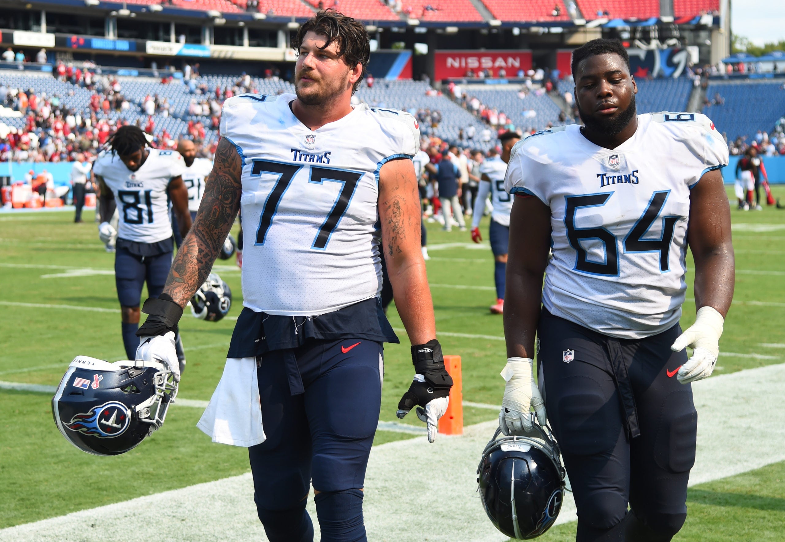 Sep 12, 2021; Nashville, Tennessee, USA; Tennessee Titans offensive tackle Taylor Lewan (77) and Tennessee Titans offensive guard Nate Davis (64) walk off the field after a loss against the Arizona Cardinals at Nissan Stadium. Mandatory Credit: Christopher Hanewinckel-USA TODAY Sports