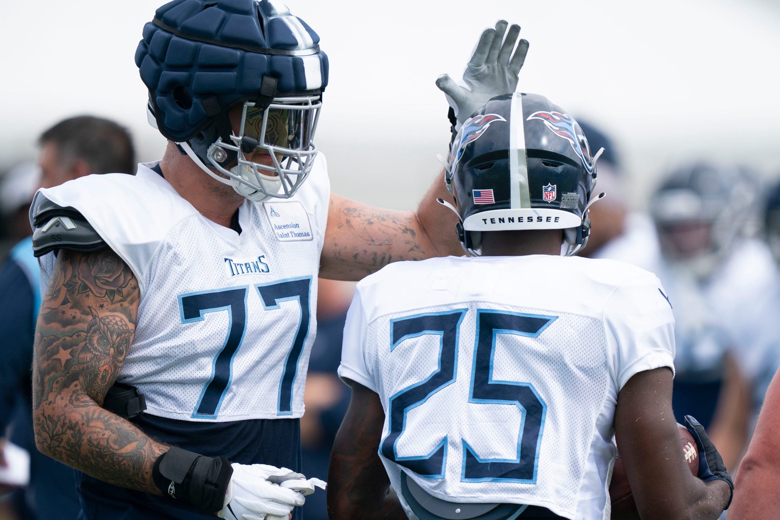 Tennessee Titans offensive tackle Taylor Lewan (77) pats running back Hassan Haskins (25) on the helmet after a drill during a training camp practice at Ascension Saint Thomas Sports Park Tuesday, Aug. 2, 2022, in Nashville, Tenn. Nas Titans 013