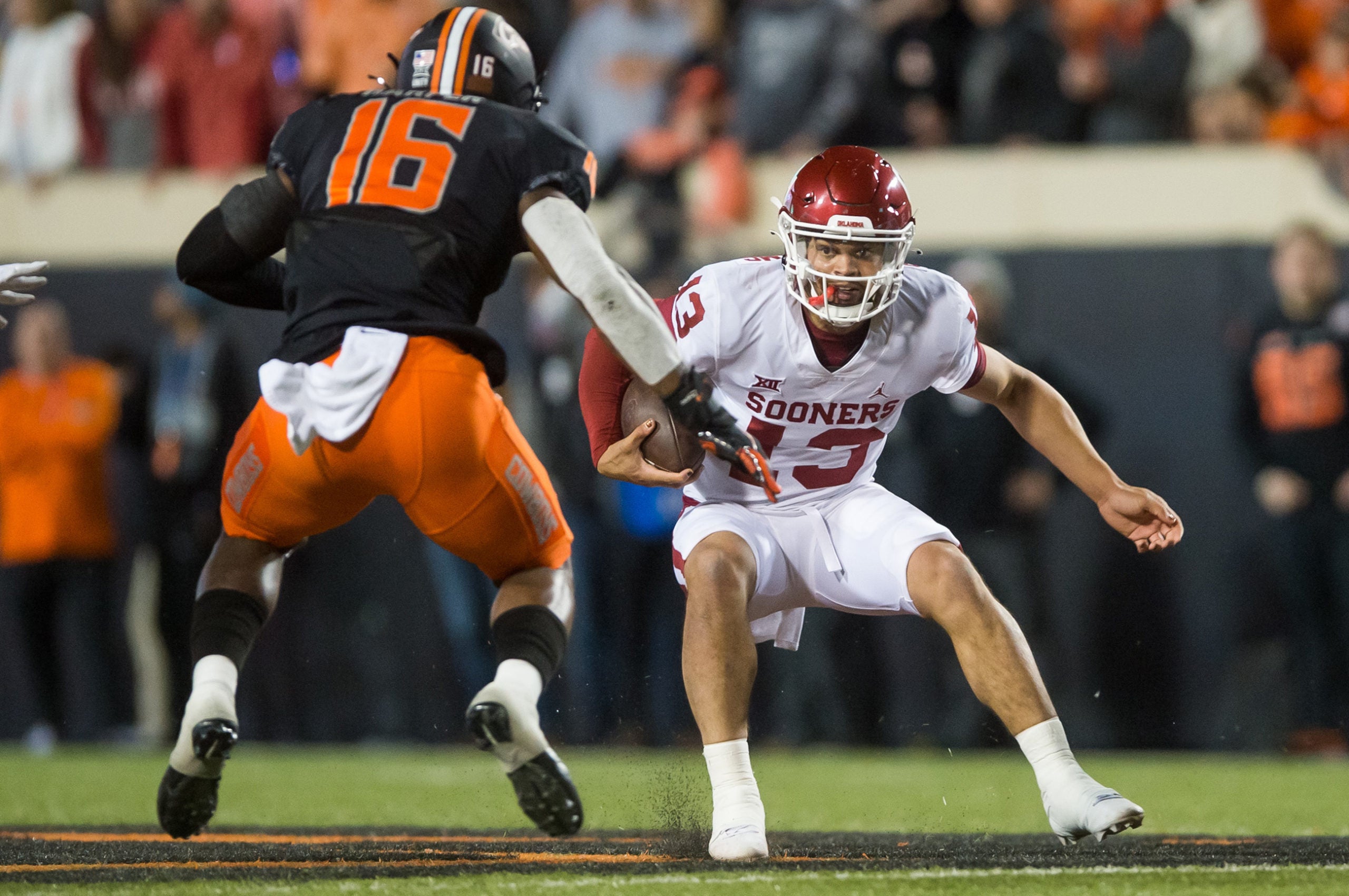 Nov 27, 2021; Stillwater, Oklahoma, USA;  Oklahoma Sooners quarterback Caleb Williams (13) runs the ball against Oklahoma State Cowboys linebacker Devin Harper (16) during the first quarter at Boone Pickens Stadium. Oklahoma State won 37-33. Mandatory Credit: Brett Rojo-USA TODAY Sports