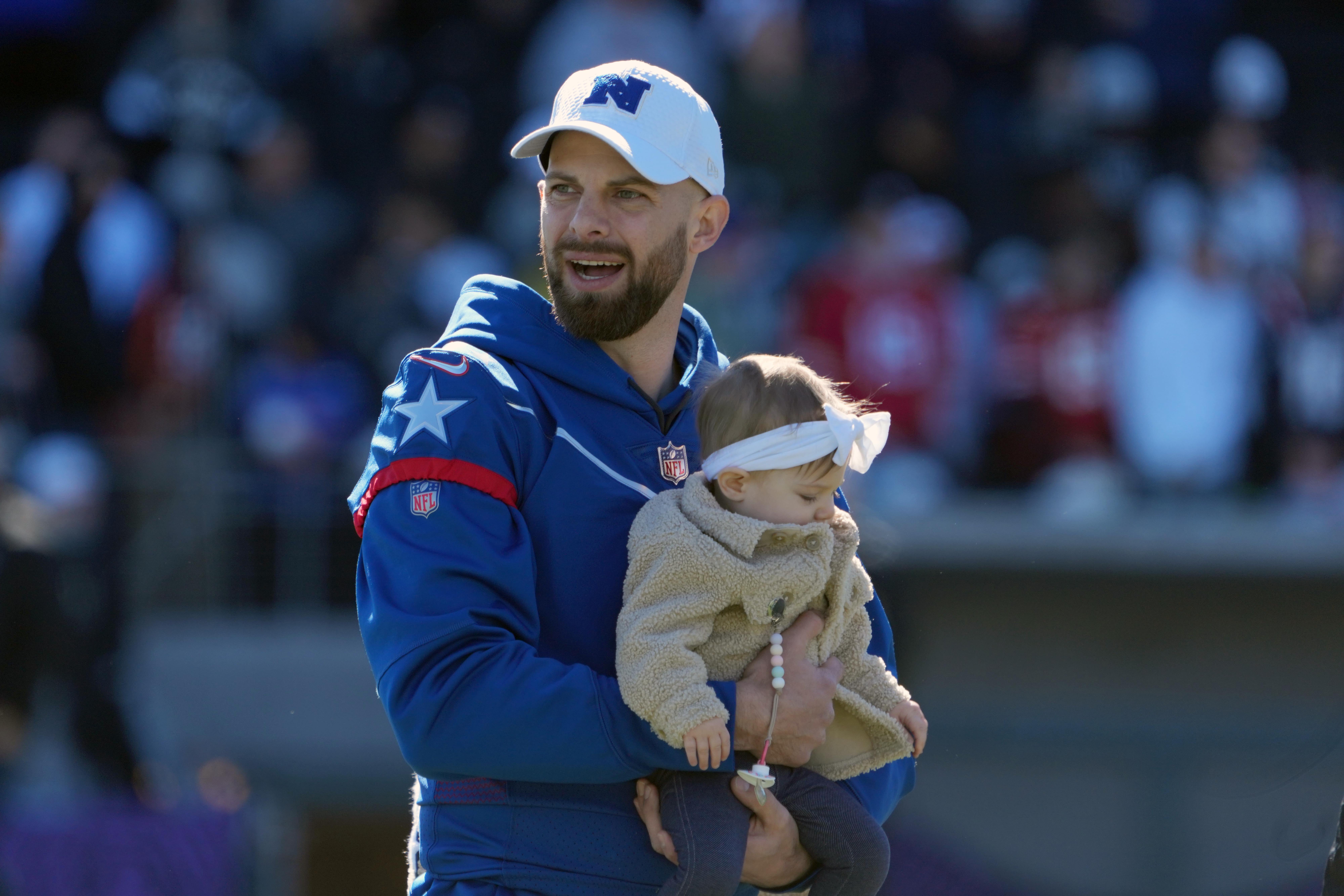 Feb 4, 2022; Las Vegas, NV, USA; Dallas Cowboys punter Bryan Anger holds a child during NFC practice at the Las Vegas Ballpark. Mandatory Credit: Kirby Lee-USA TODAY Sports