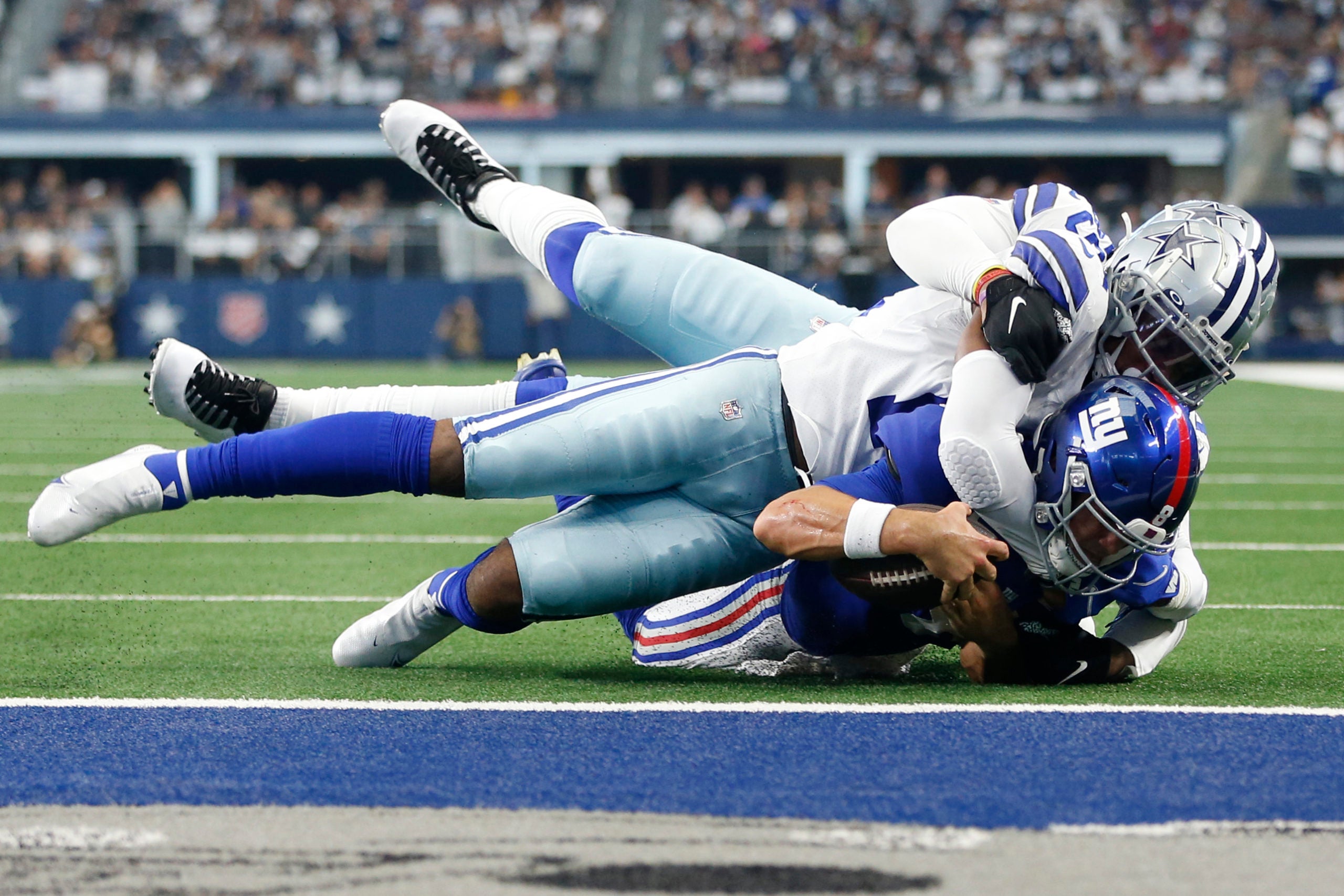 Oct 10, 2021; Arlington, Texas, USA; New York Giants quarterback Daniel Jones (8) is tackled by Dallas Cowboys linebacker Jabril Cox (14) and defensive end Chauncey Golston (59) in the second quarter at AT&T Stadium. Mandatory Credit: Tim Heitman-USA TODAY Sports