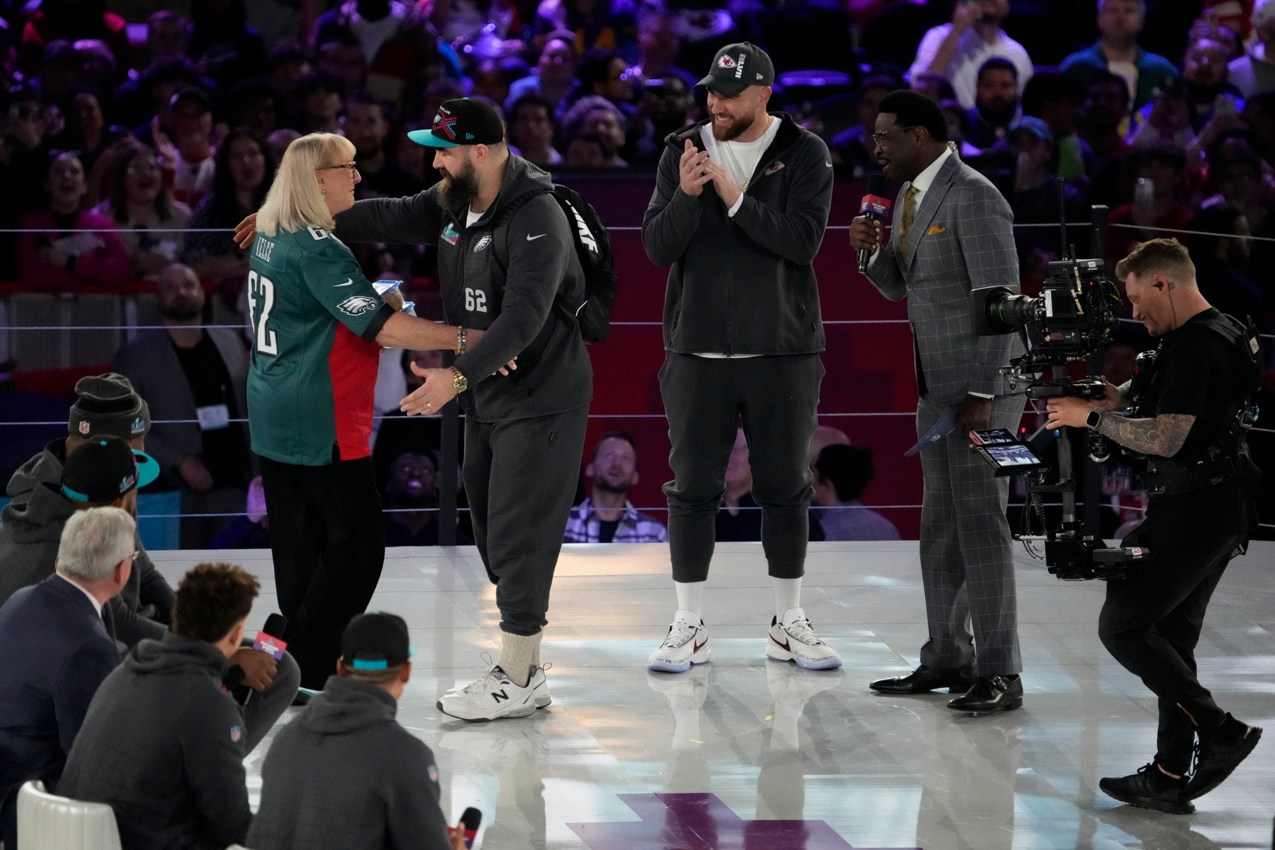 Feb 6, 2023; Phoenix, AZ, USA;  Donna Kelce hugs her son Philadelphia Eagles center Jason Kelce (62) while her other son Kansas City Chiefs tight end Travis Kelce (87) claps during Super Bowl Opening Night at Footprint Center. Mandatory Credit: Cheryl Evans-USA TODAY Sports