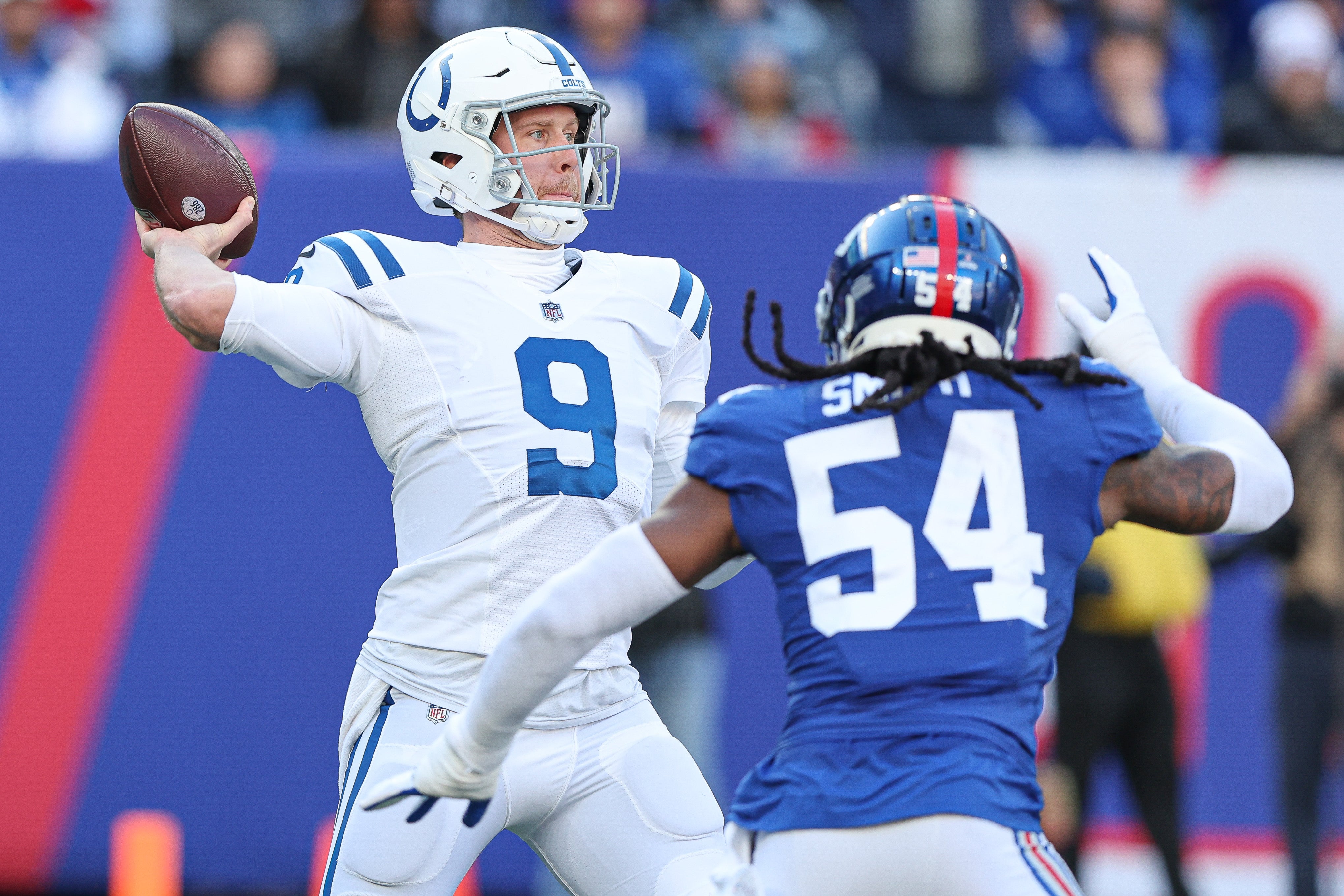 Jan 1, 2023; East Rutherford, New Jersey, USA; Indianapolis Colts quarterback Nick Foles (9) throws the ball as New York Giants linebacker Jaylon Smith (54) pursues during the first half at MetLife Stadium.