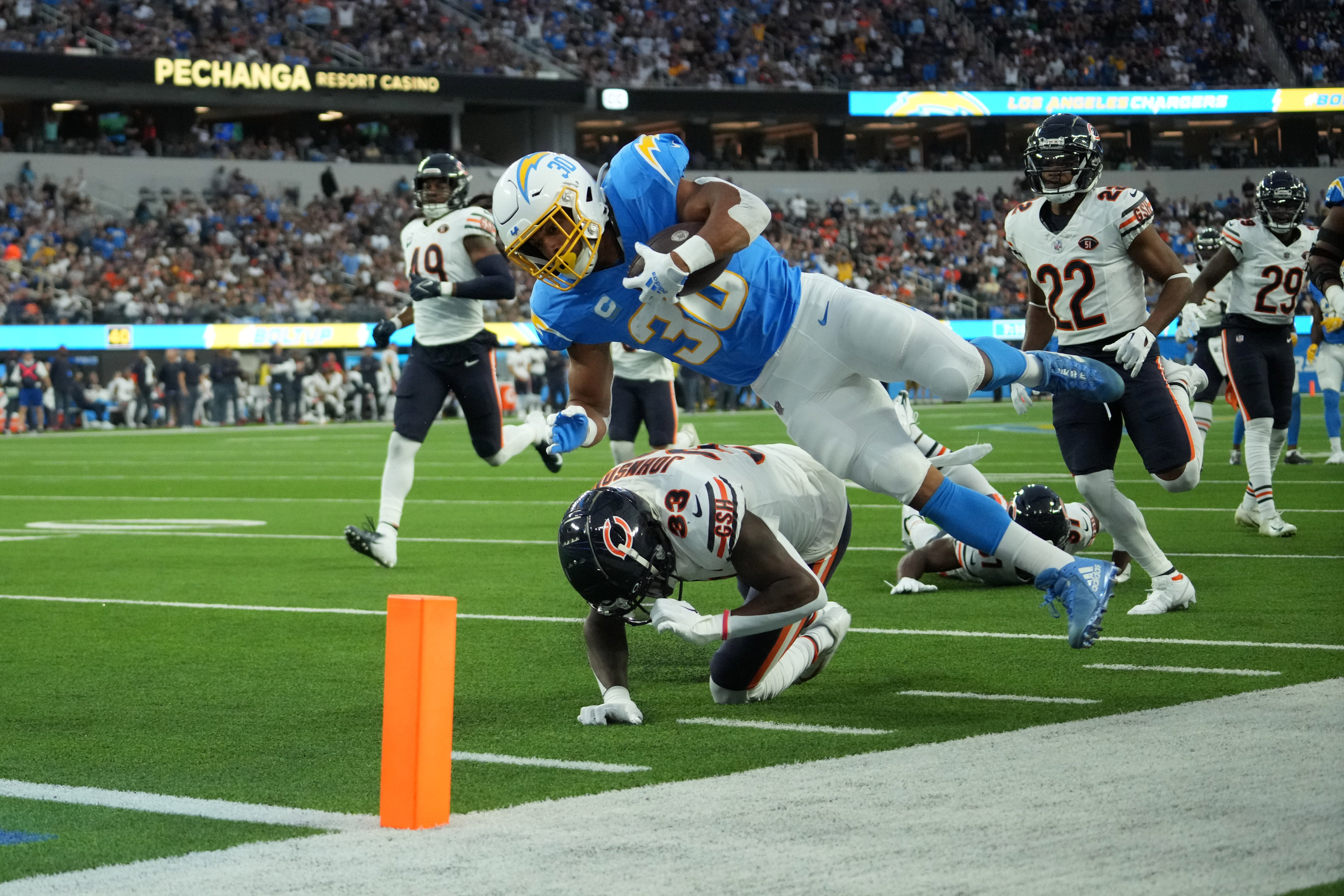 Oct 29, 2023; Inglewood, California, USA; Los Angeles Chargers running back Austin Ekeler (30) dives over Chicago Bears cornerback Jaylon Johnson (33) to score on a 39-yard touchdown run in the first half at SoFi Stadium.
