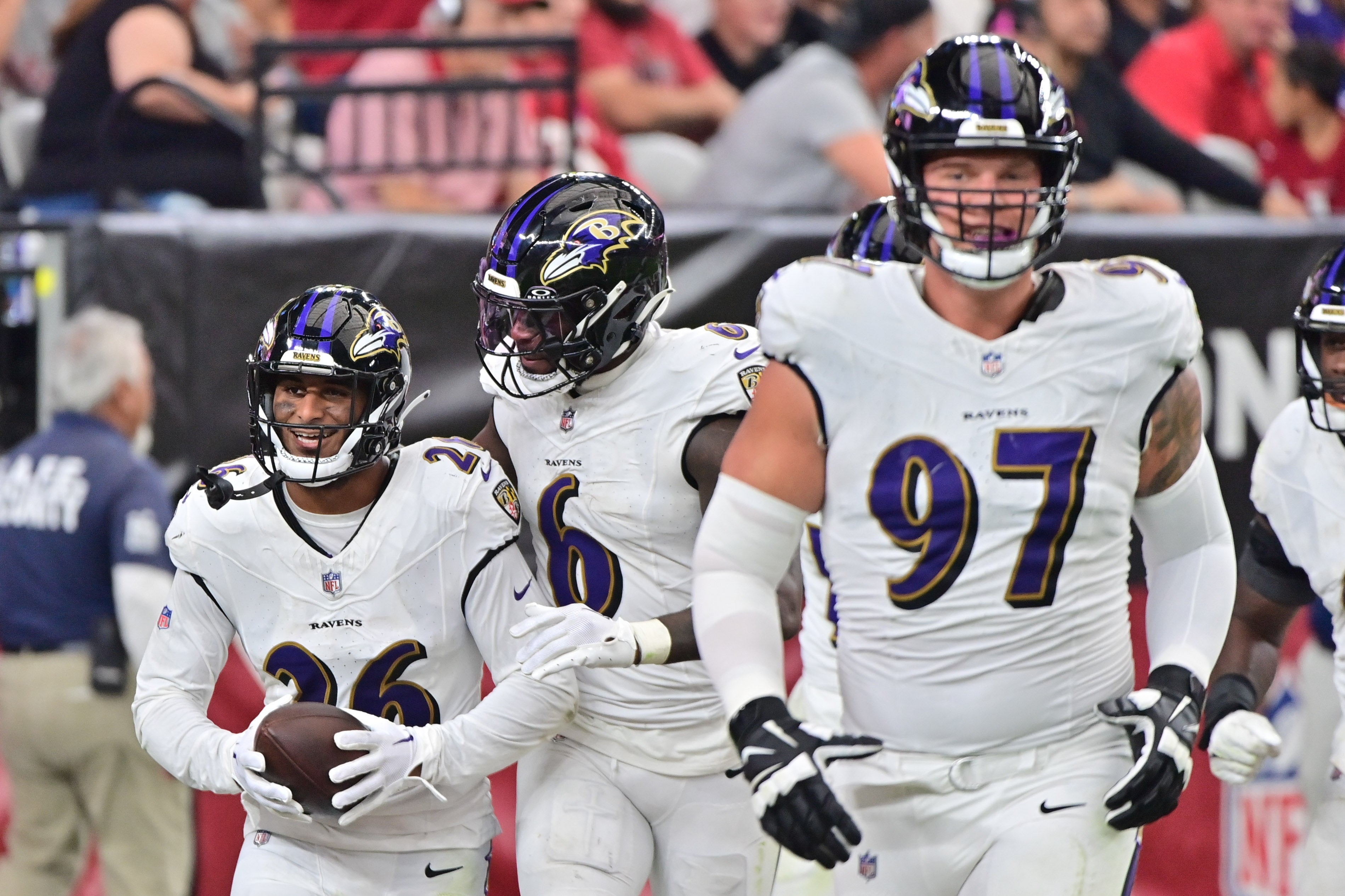 Baltimore Ravens safety Geno Stone (26) celebrates with linebacker Patrick Queen (6) and defensive end Brent Urban (97) after intercepting a pass in the second half against the Arizona Cardinals at State Farm Stadium.