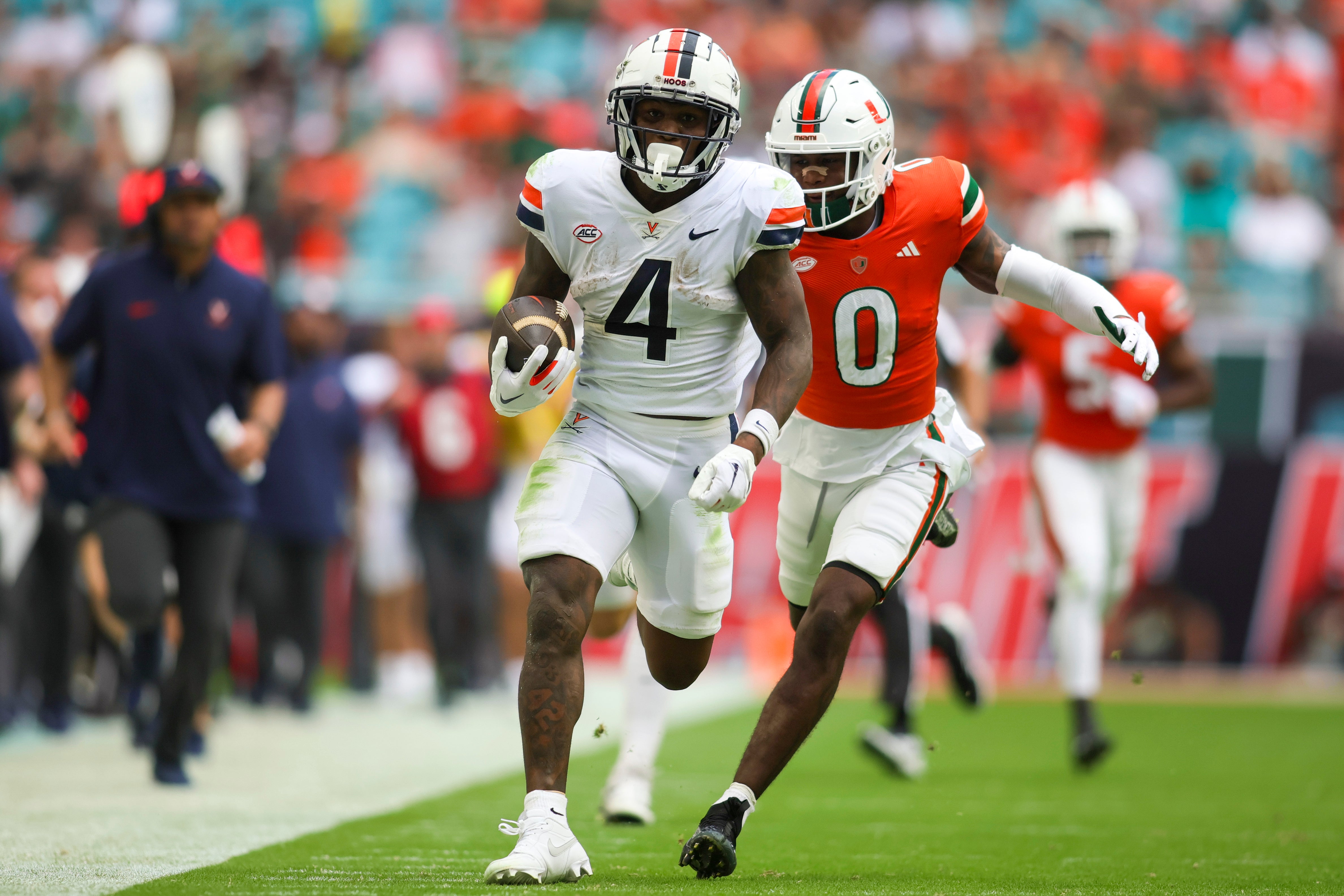 Oct 28, 2023; Miami Gardens, Florida, USA; Virginia Cavaliers wide receiver Malik Washington (4) runs with the football ahead of Miami Hurricanes cornerback Te'Cory Couch (0) during the second quarter at Hard Rock Stadium.