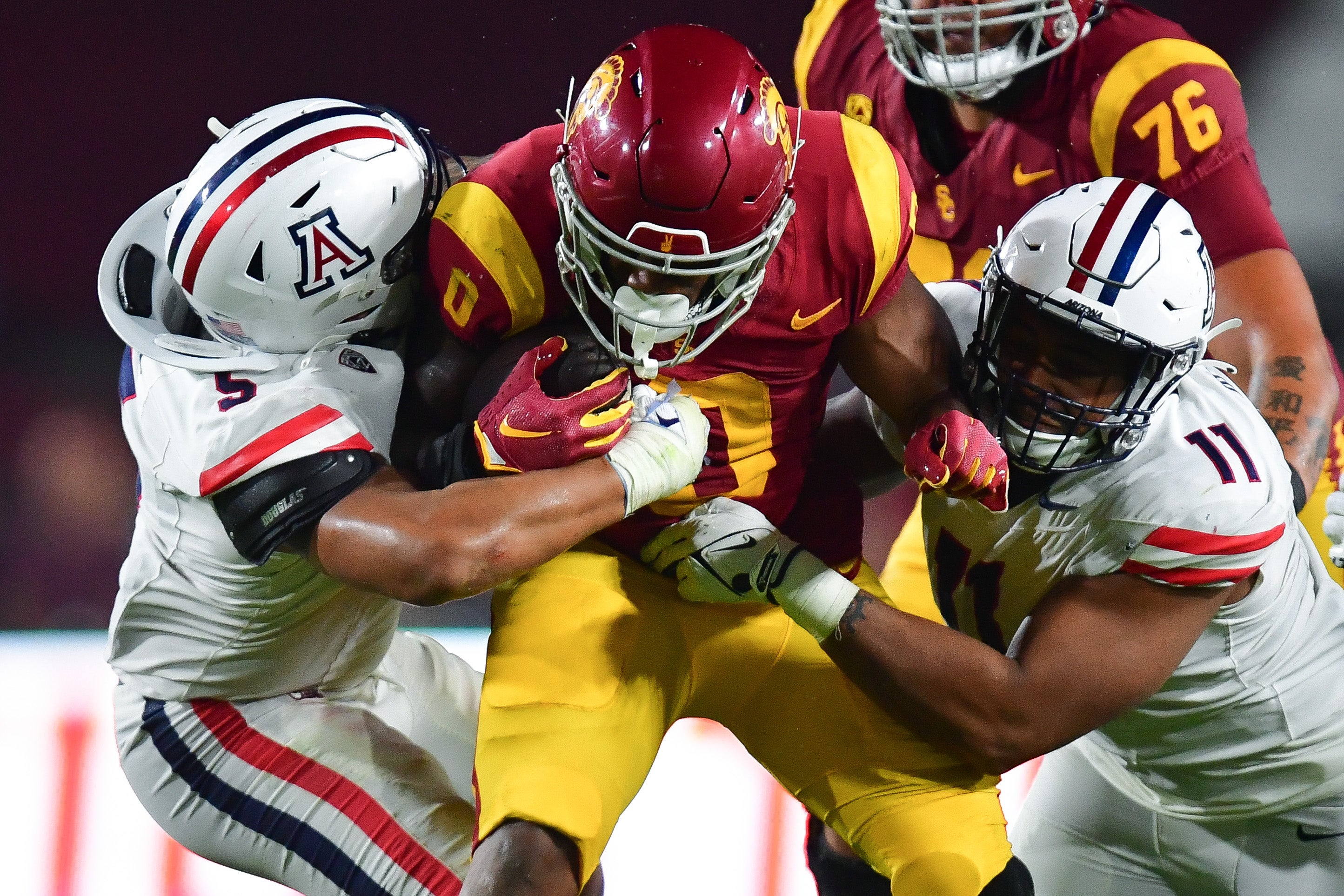 Southern California Trojans running back MarShawn Lloyd (0) is brought down by Arizona Wildcats linebacker Jacob Manu (5) and linebacker Taylor Upshaw (11) during the second half at Los Angeles Memorial Coliseum.