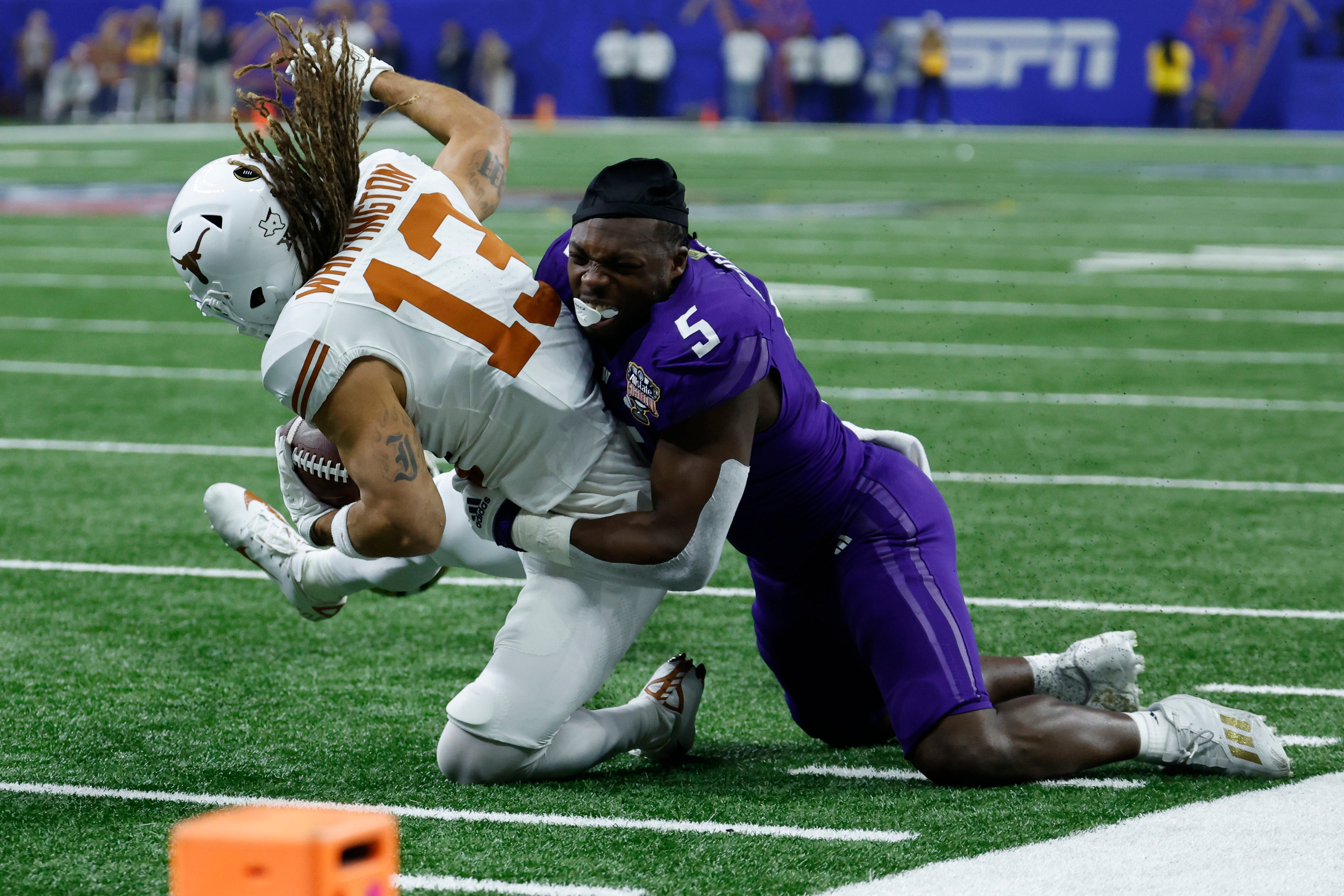 Washington Huskies linebacker Edefuan Ulofoshio (5) tackles Texas Longhorns wide receiver Jordan Whittington (13) after losing his helmet in the 2024 Sugar Bowl college football playoff semifinal game at Caesars Superdome.