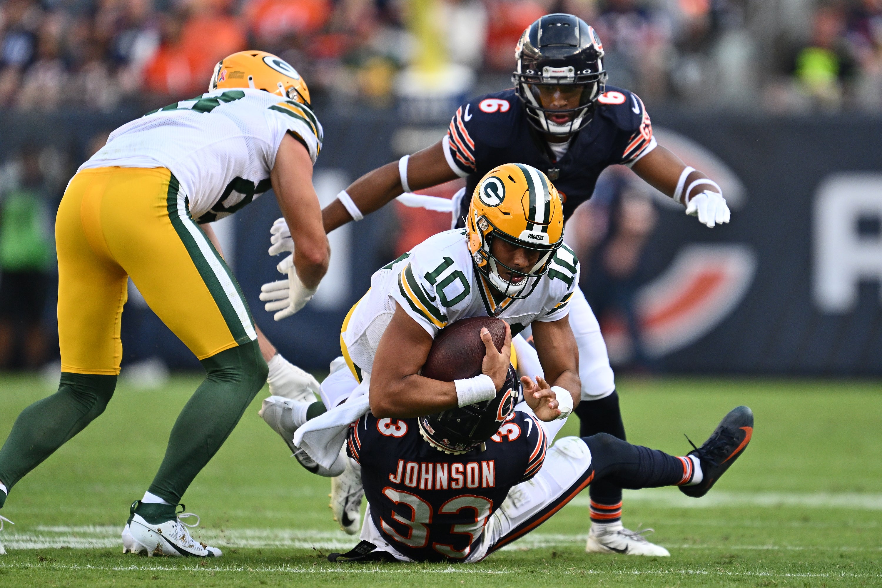 Sep 10, 2023; Chicago, Illinois, USA; Green Bay Packers quarterback Jordan Love (10) is dragged down by Chicago Bears defensive back Jaylon Johnson (33) in the second half at Soldier Field.