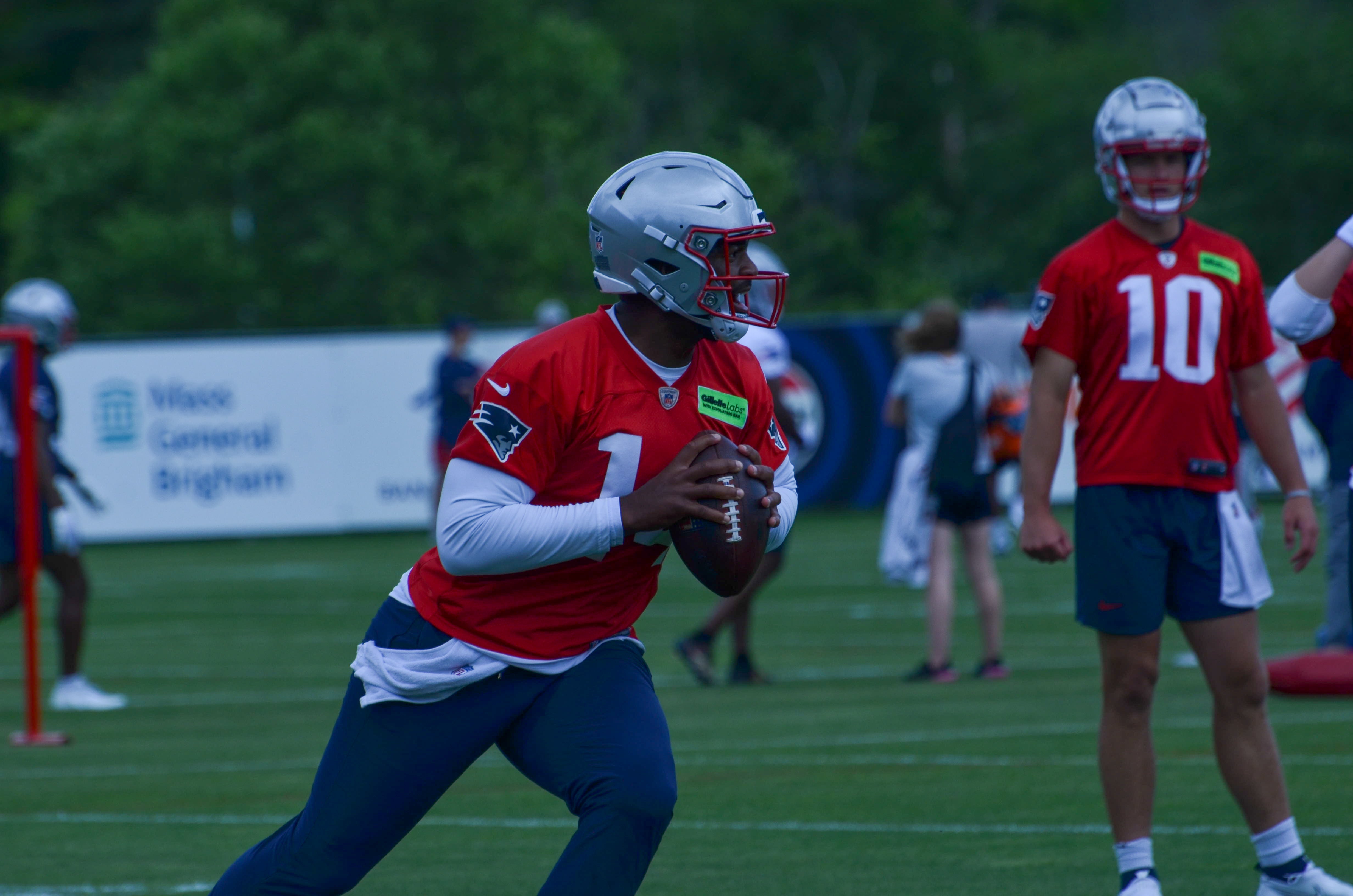 Patriots QB Jacoby Brissett gets ready to throw the ball as QB Drake Maye looks on - May 29, 2024