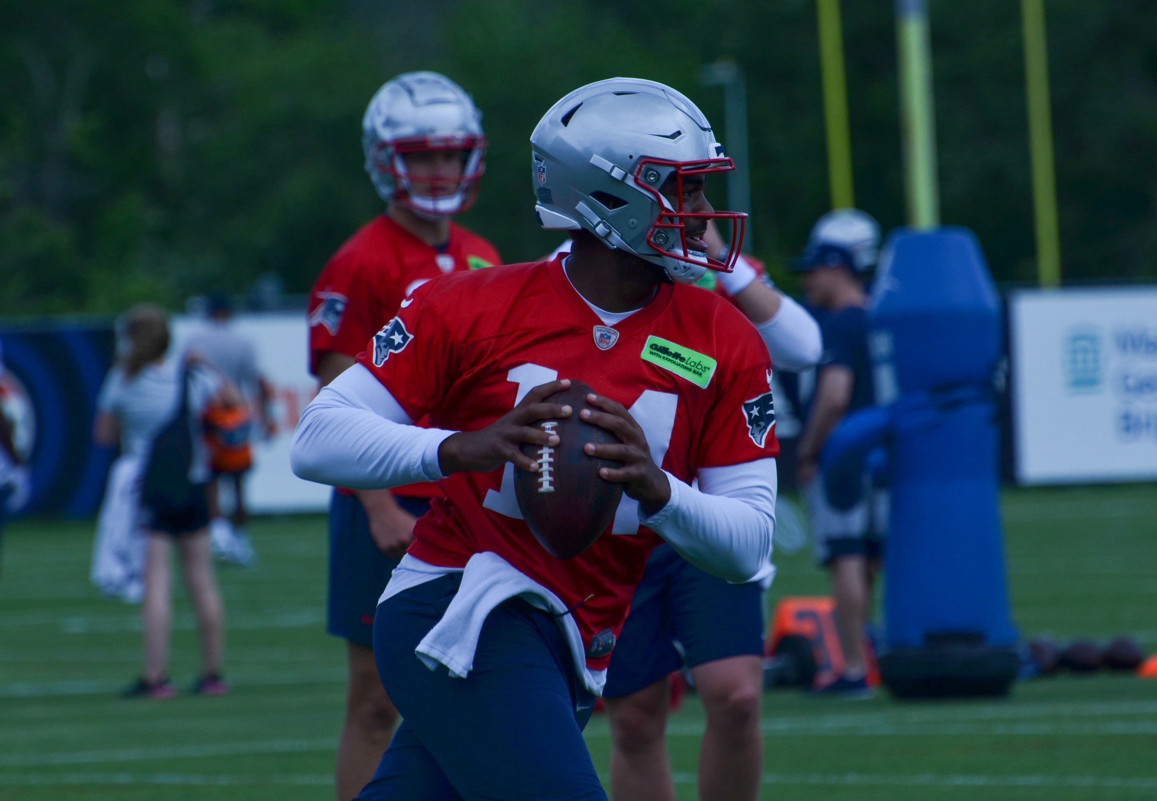 Patriots QB Jacoby Brissett gets ready to throw the ball as QB Drake Maye looks on - May 29, 2024
