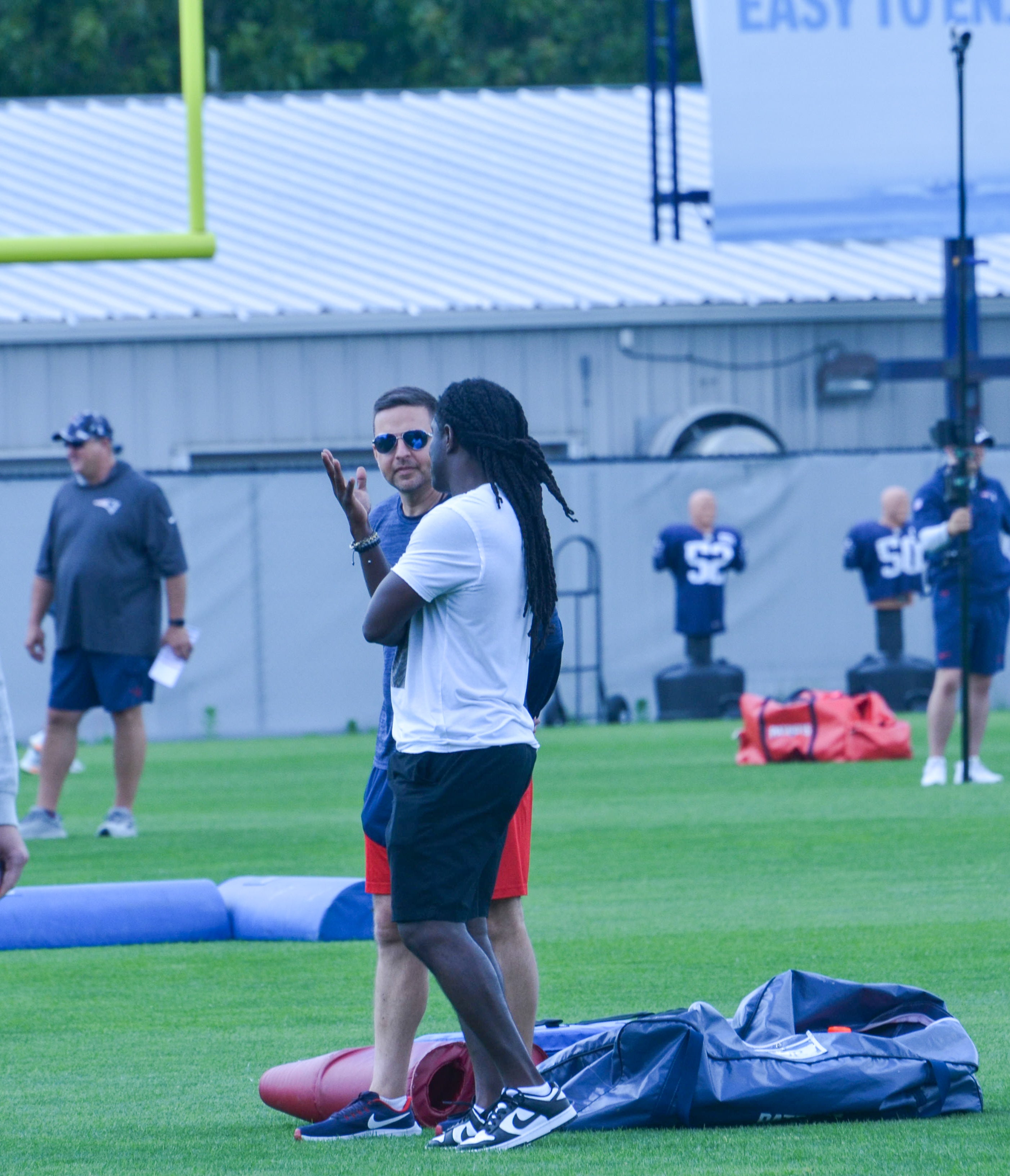 Patriots legend Deion Branch talks with Eliot Wolf during the final day of mandatory minicamp - June 12, 2024