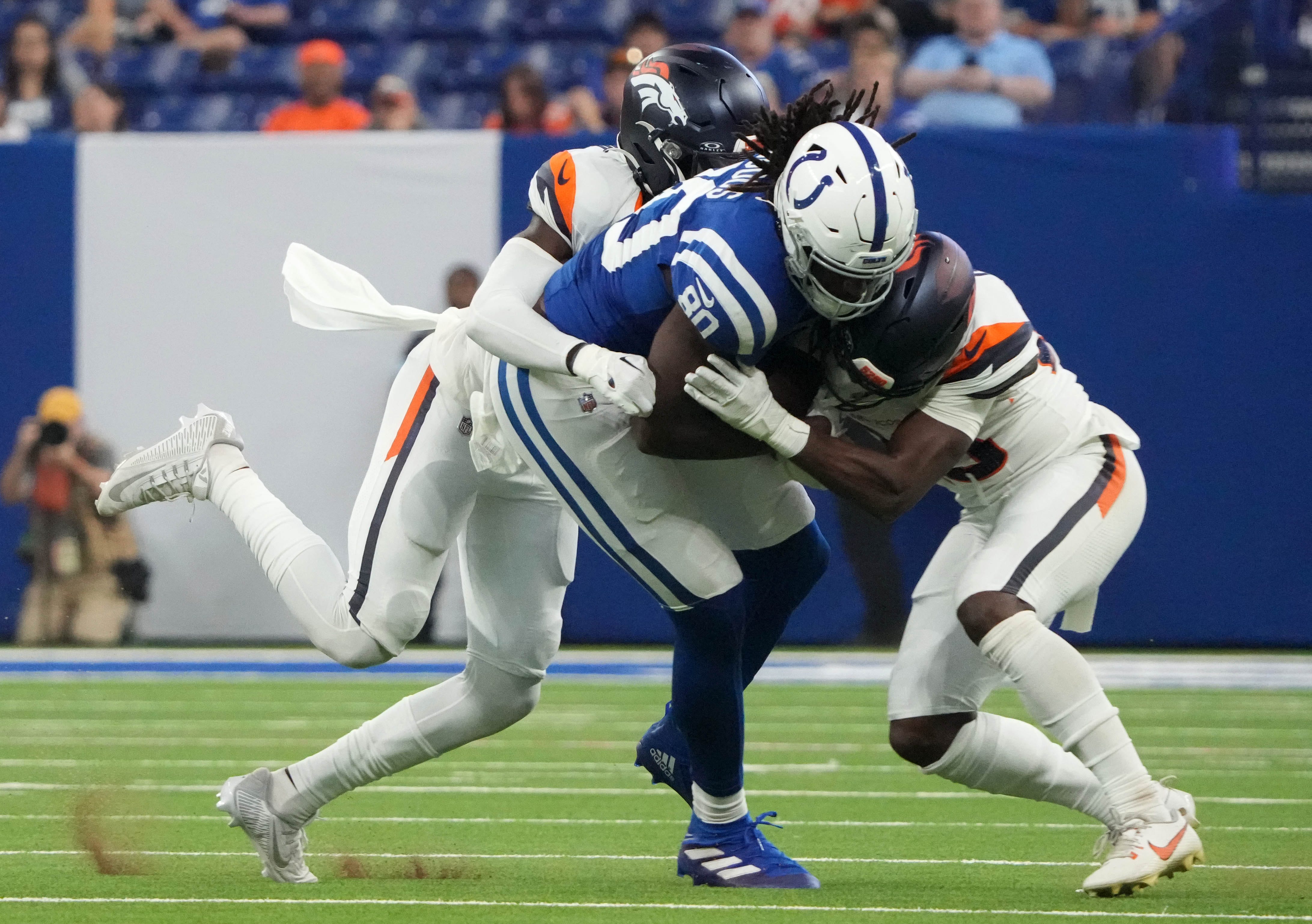Indianapolis Colts tight end Jelani Woods (80) is tackled by Denver Broncos safety JL Skinner (34) and cornerback Art Green (28) during the second half of a preseason game Sunday, Aug. 11, 2024, at Lucas Oil Stadium in Indianapolis. The Broncos defeated the Colts 34-30.  