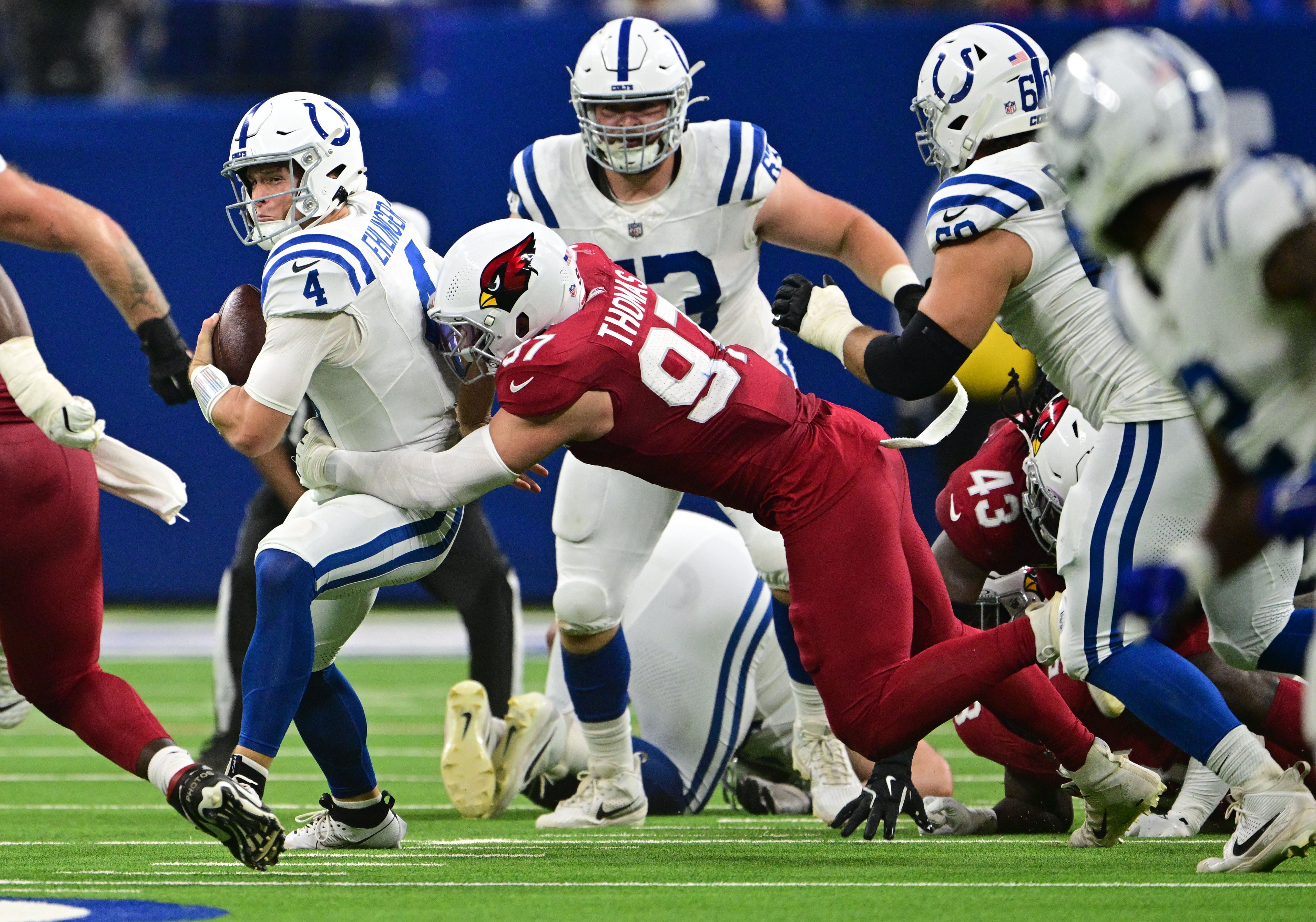 Aug 17, 2024; Indianapolis, Indiana, USA; Indianapolis Colts quarterback Sam Ehlinger (4) is sacked by Arizona Cardinals linebacker Cameron Thomas (97) during the second quarter at Lucas Oil Stadium.