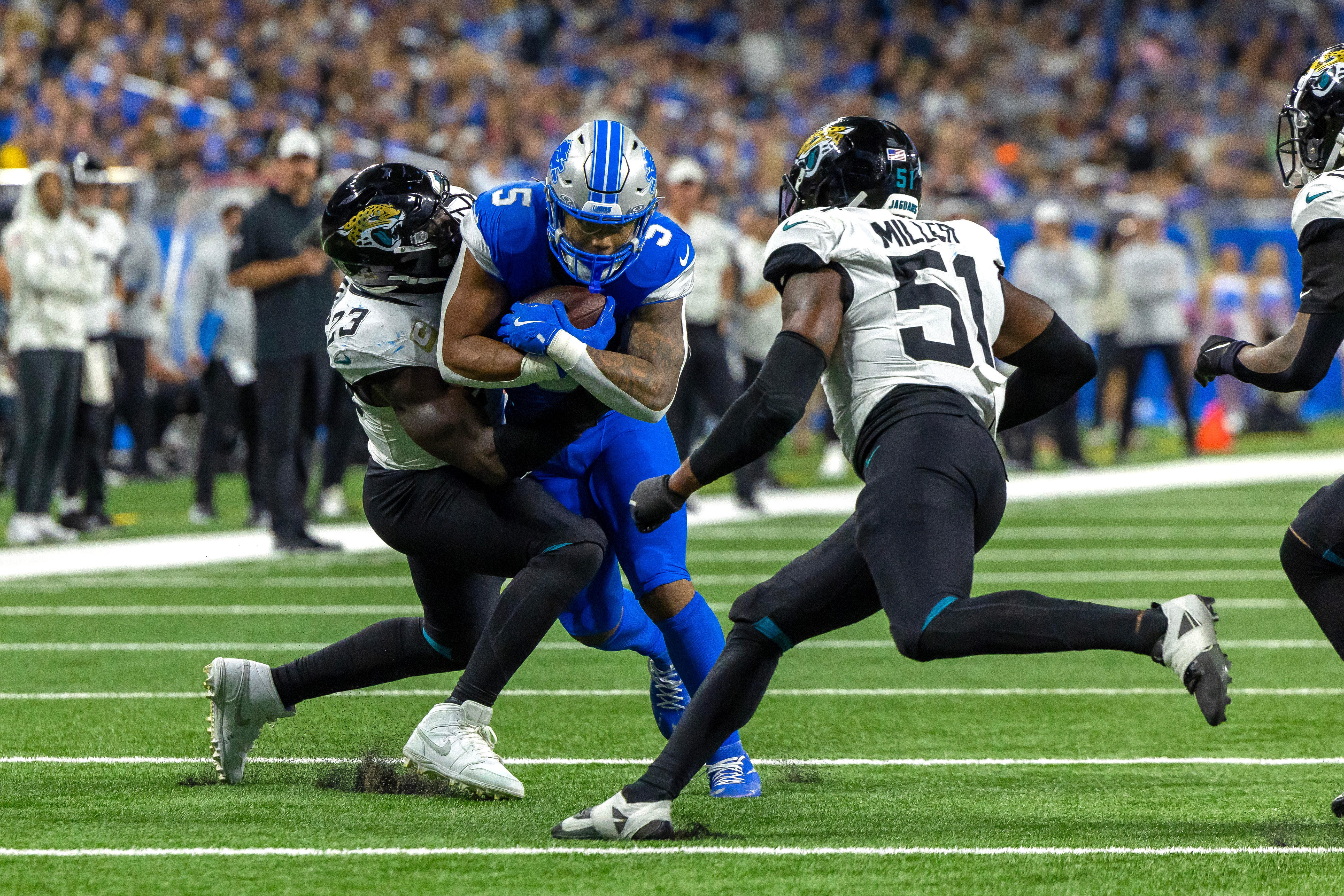 Nov 17, 2024; Detroit, Michigan, USA; Detroit Lions running back David Montgomery (5) runs with the ball and is tackles by Jacksonville Jaguars linebacker Foyesade Oluokun (23) and linebacker Ventrell Miller (51) during the first half at Ford Field.