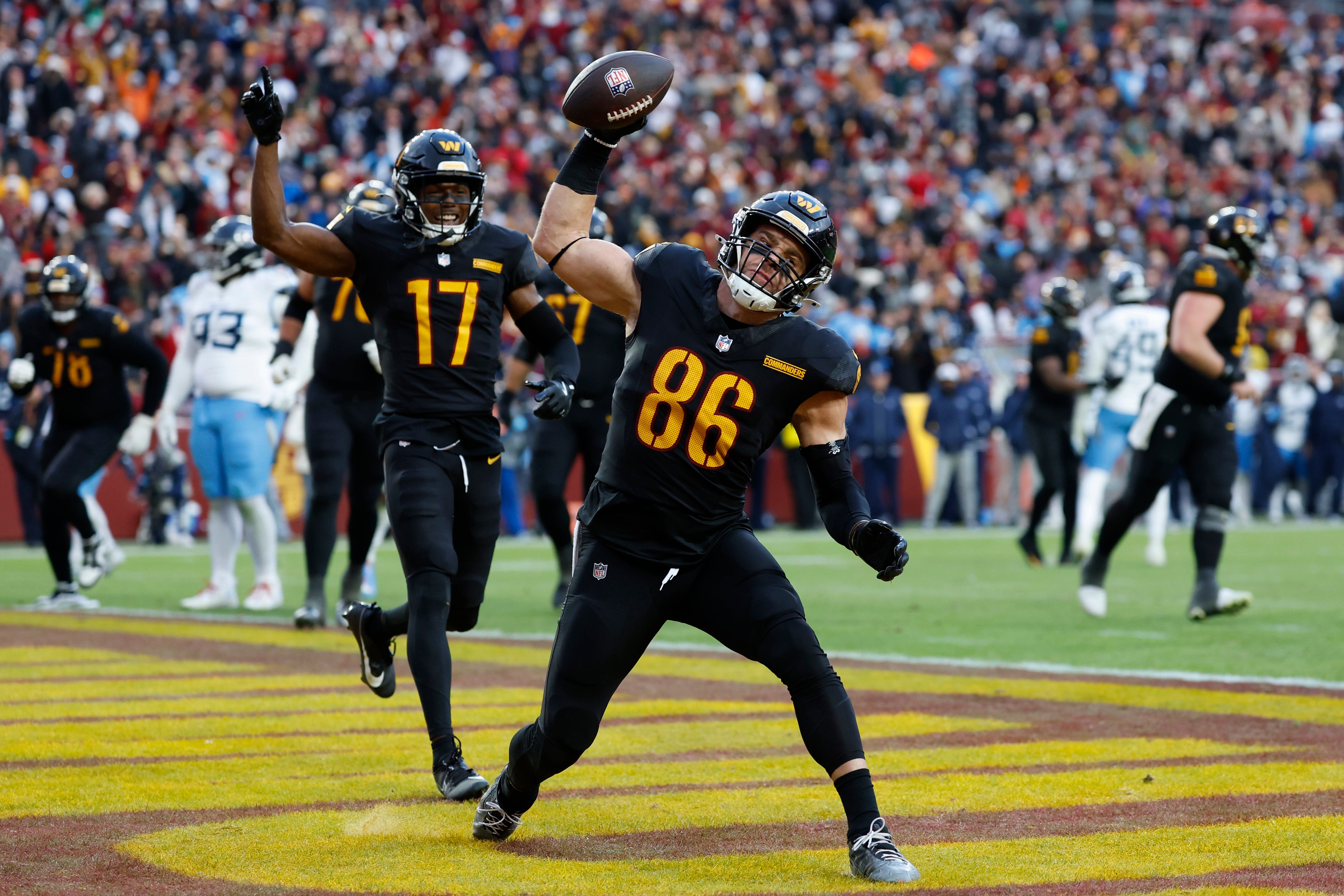Dec 1, 2024; Landover, Maryland, USA; Washington Commanders tight end Zach Ertz (86) spikes the ball in the end zone after catching a touchdown pass as Commanders wide receiver Terry McLaurin (17) celebrates against the Tennessee Titans during the fourth quarter at Northwest Stadium.