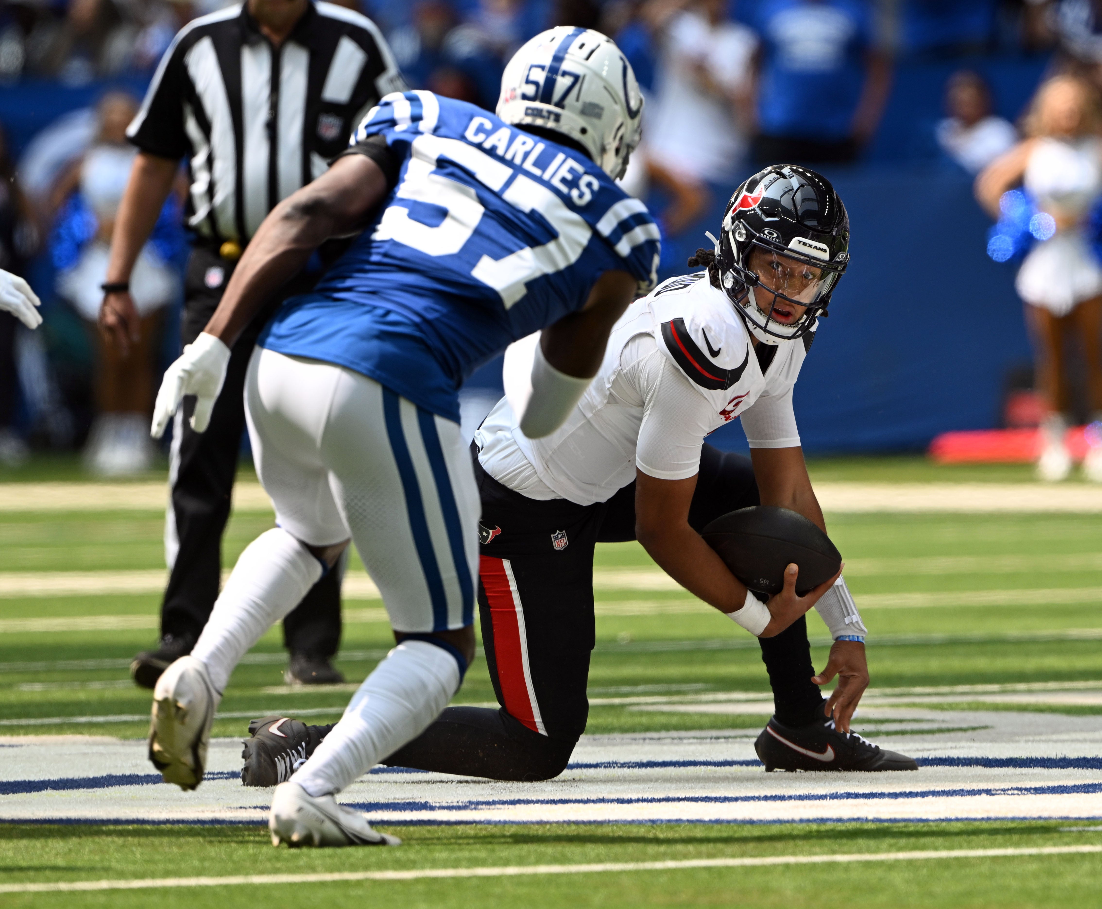 Sep 8, 2024; Indianapolis, Indiana, USA; Houston Texans quarterback C.J. Stroud (7) stumbles in front of Indianapolis Colts linebacker Jaylon Carlies (57) during the first quarter at Lucas Oil Stadium.