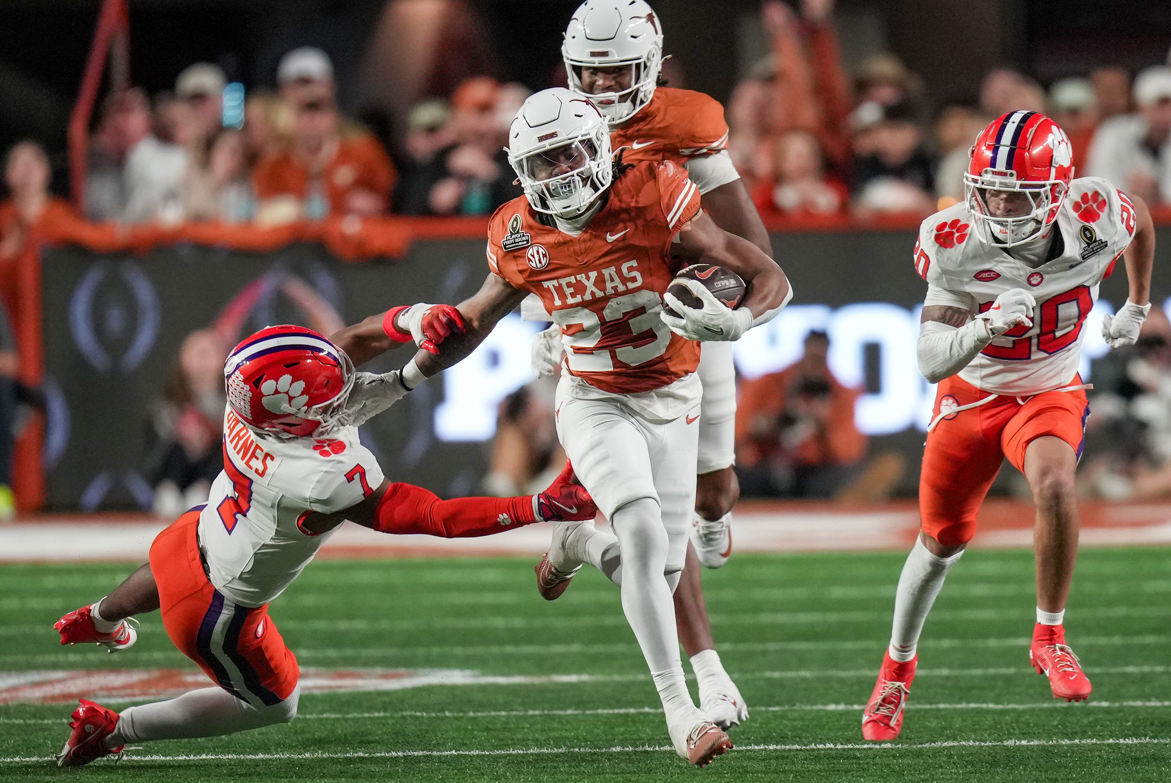 Texas Longhorns running back Jaydon Blue (23) stiff arms Clemson Tigers safety Khalil Barnes (7) as he runs toward the end zone in the second half of an NCAA College Football Playoffs first round game.