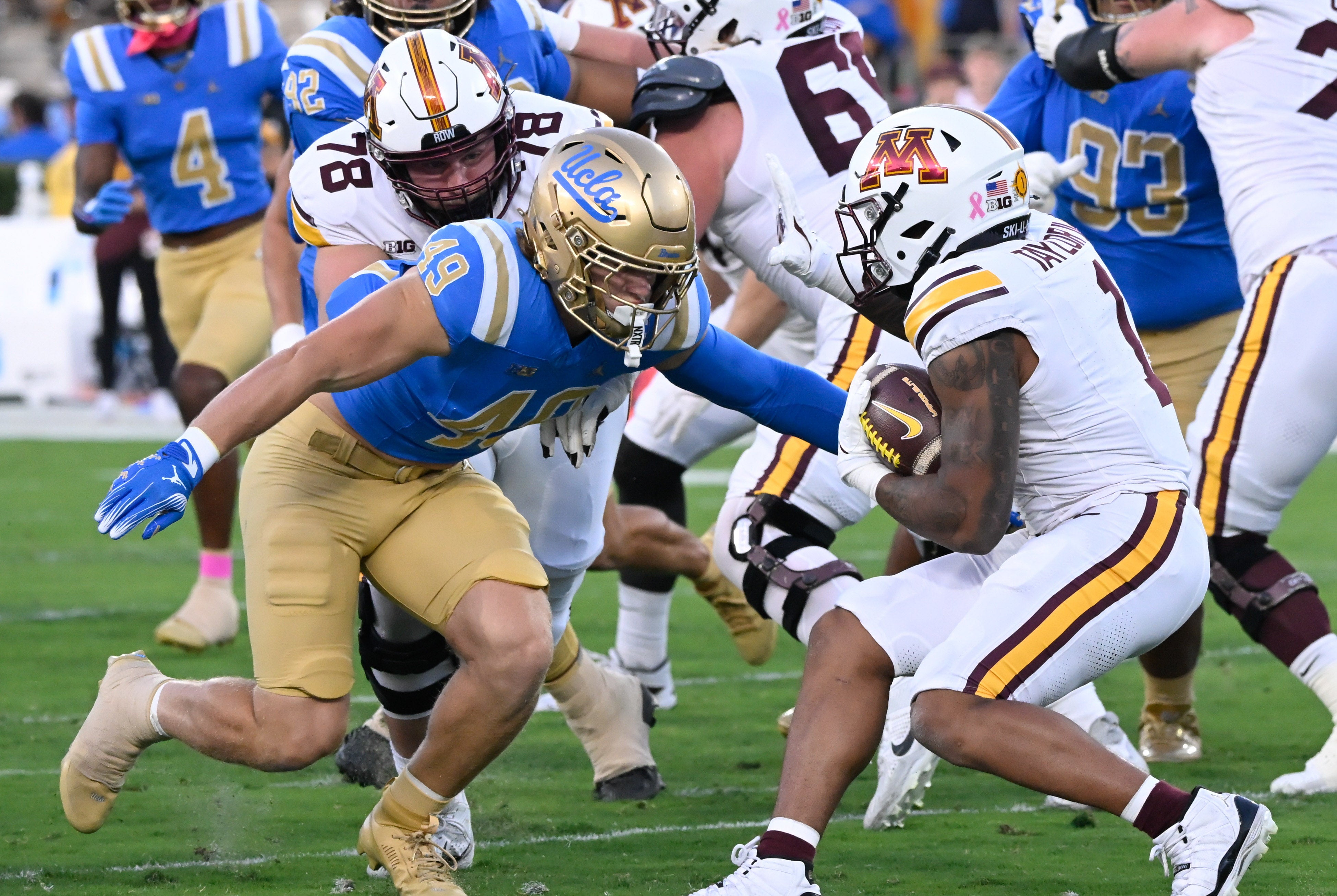 Oct 12, 2024; Pasadena, California, USA; UCLA Bruins linebacker Carson Schwesinger (49) moves to tackle Minnesota Golden Gophers running back Darius Taylor (1) during the first half at Rose Bowl.