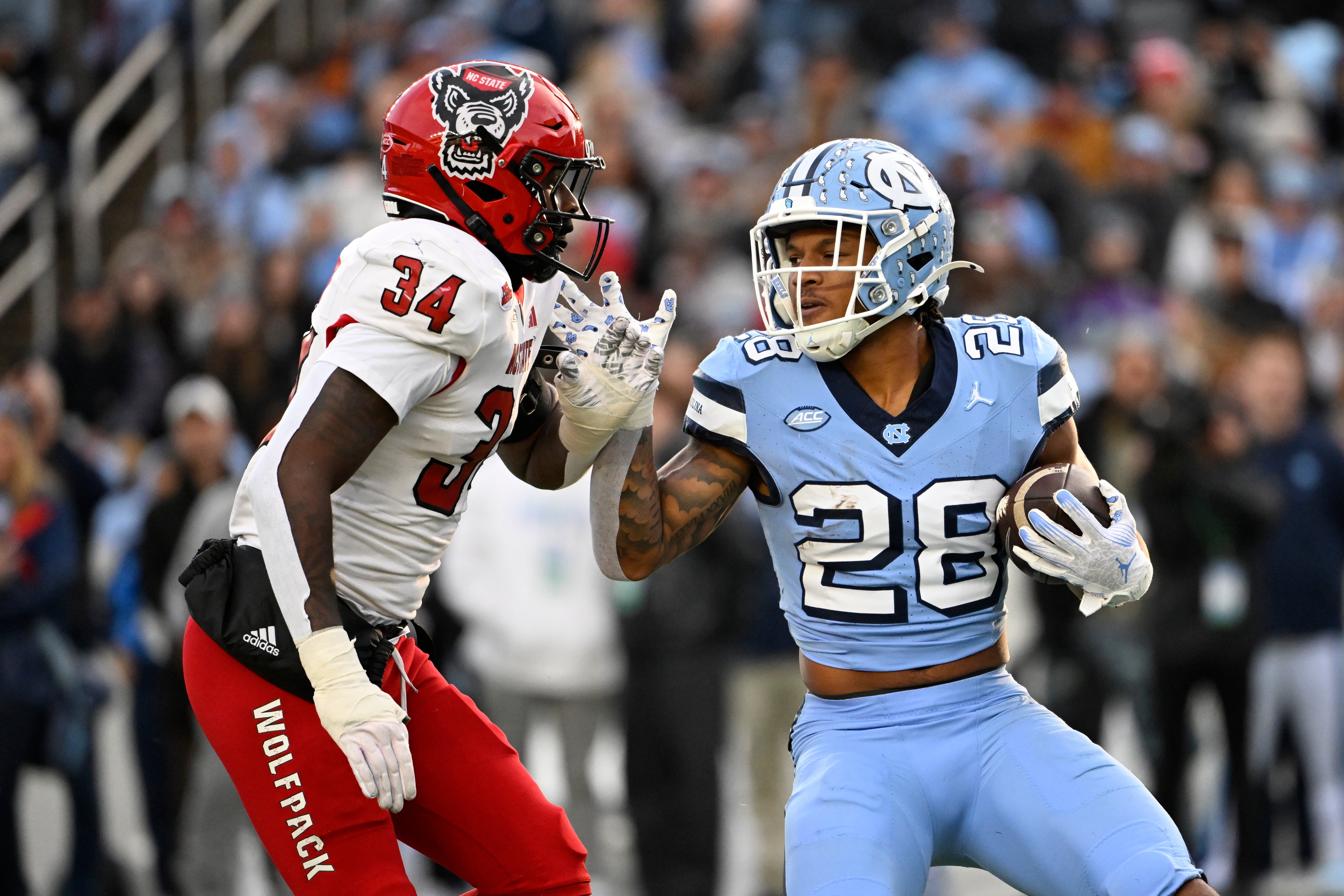 Nov 30, 2024; Chapel Hill, North Carolina, USA; North Carolina Tar Heels running back Omarion Hampton (28) with the ball as North Carolina State Wolfpack linebacker Kamal Bonner (34) defends in the first quarter at Kenan Memorial Stadium.