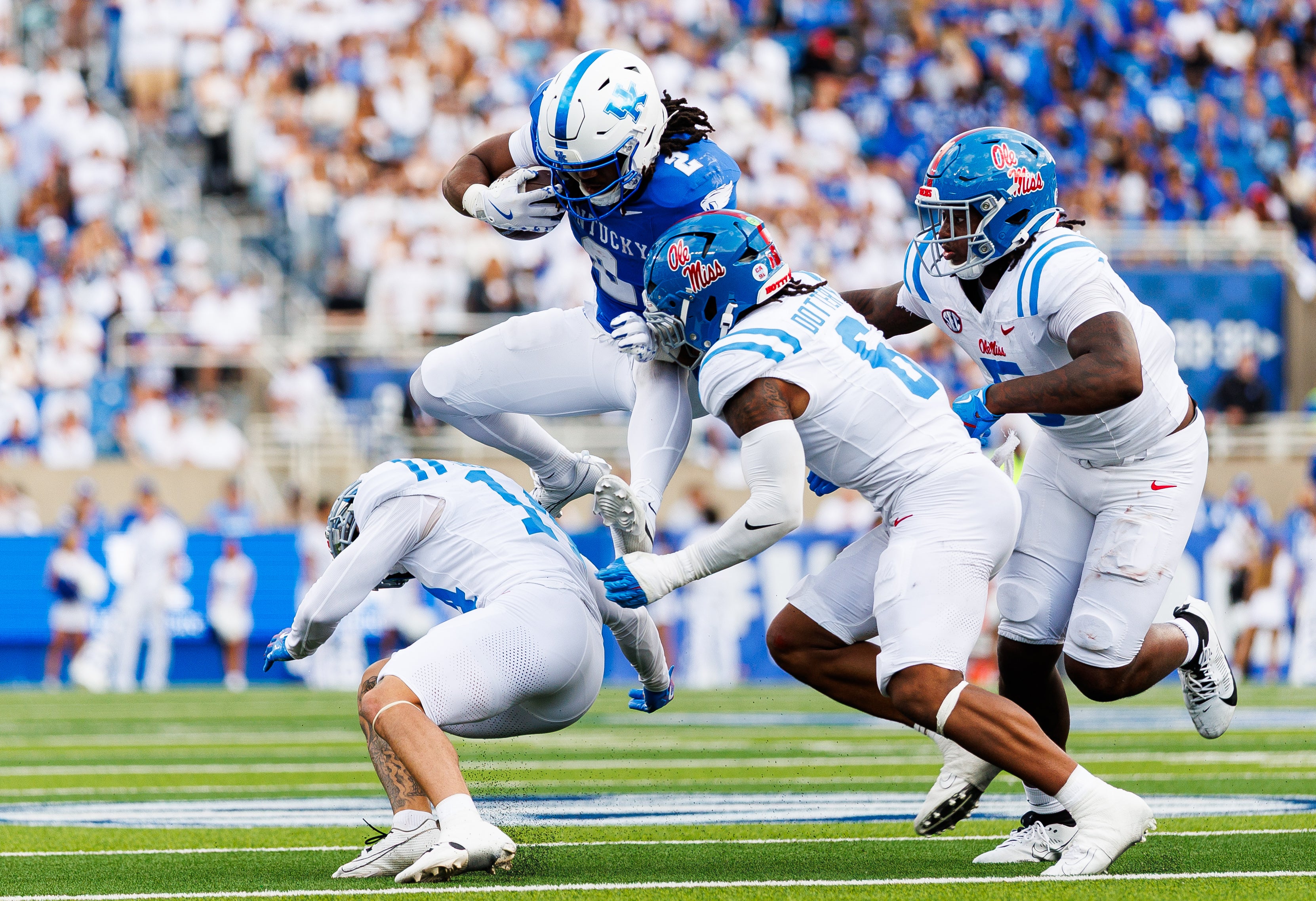 Sep 6, 2025; Lexington, Kentucky, USA; Kentucky Wildcats running back Dante Dowdell (2) attempts to run the ball against Mississippi Rebels safety Kapena Gushiken (14), linebacker TJ Dottery (6) and defensive end Kam Franklin (5) during the second quarter at Kroger Field.