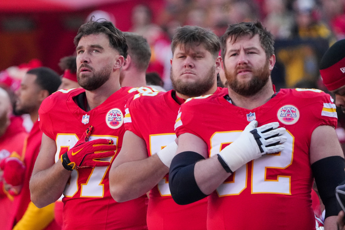 Ngày 29 tháng 11 năm 2024; Kansas City, Missouri, Hoa Kỳ; Tiền vệ biên Travis Kelce (87), tiền vệ trung tâm Creed Humphrey (52) và hậu vệ Joe Thuney (62) của đội Kansas City Chiefs đứng chào quốc ca trước trận đấu với đội Las Vegas Raiders tại Sân vận động GEHA thuộc Sân vận động Arrowhead.