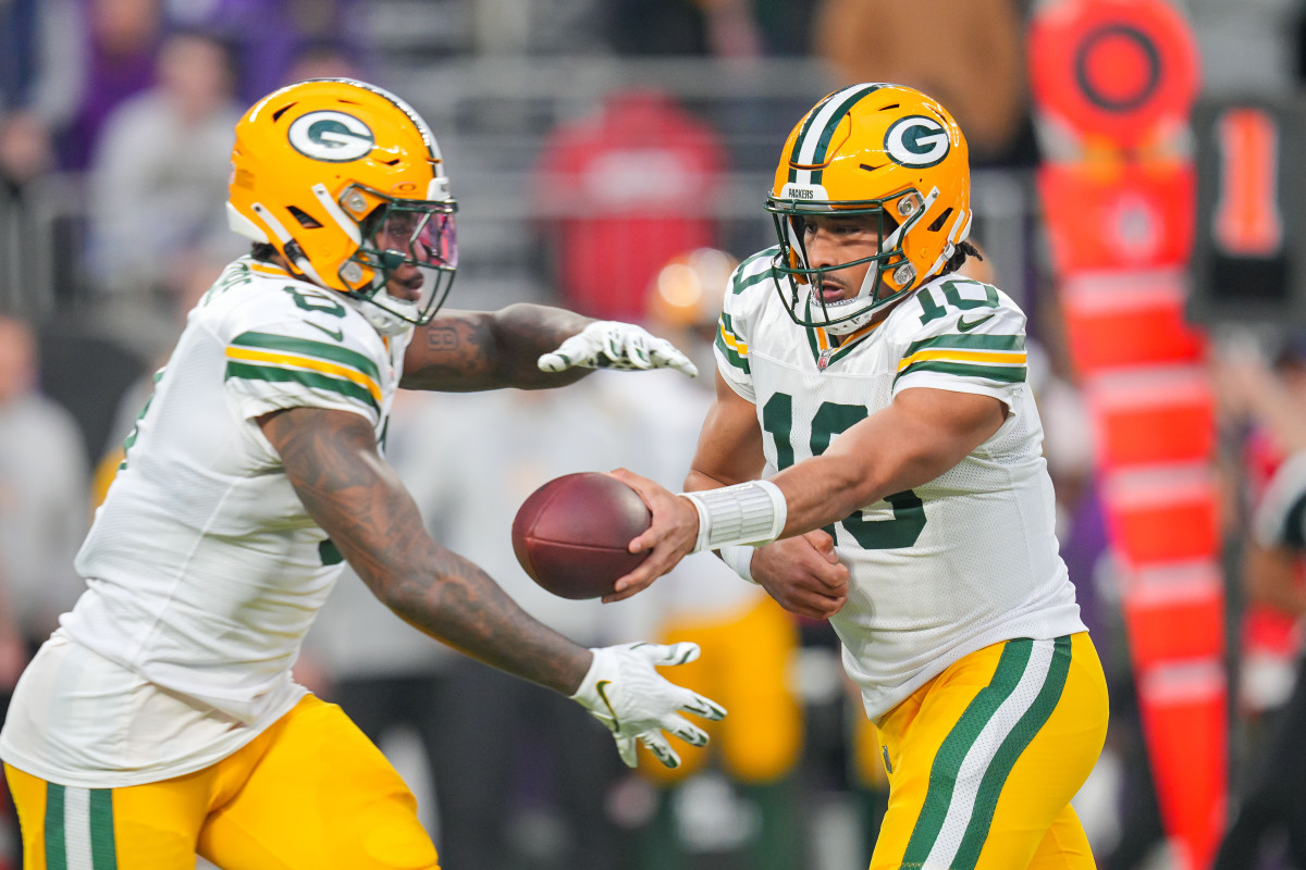 Green Bay Packers quarterback Jordan Love (10) hands the ball off to running back Josh Jacobs (8) against Minnesota Vikings in the first quarter at U.S. Bank Stadium.