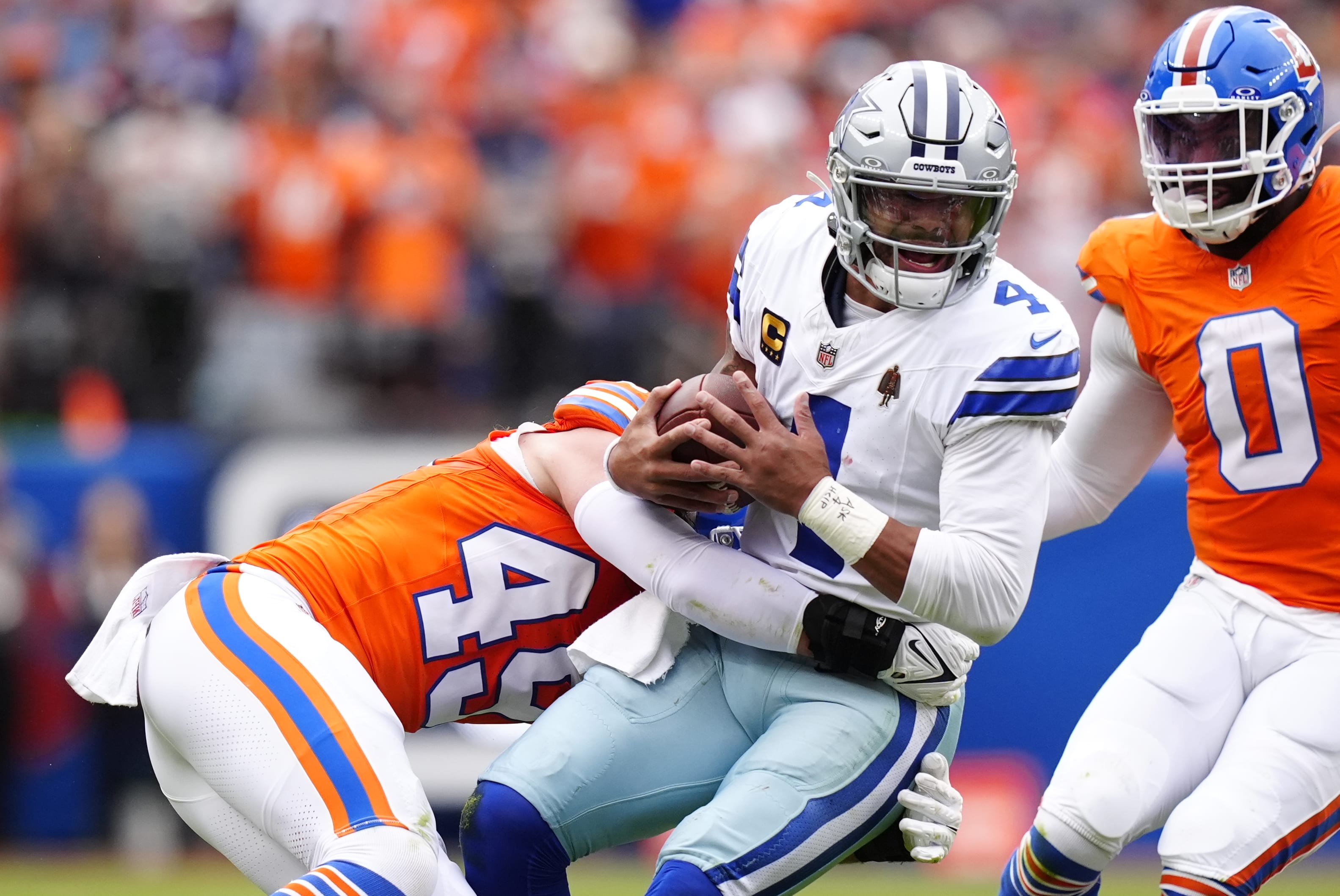 Oct 26, 2025; Denver, Colorado, USA; Denver Broncos linebacker Alex Singleton (49) tackles Dallas Cowboys quarterback Dak Prescott (4) in the first half at Empower Field at Mile High.
