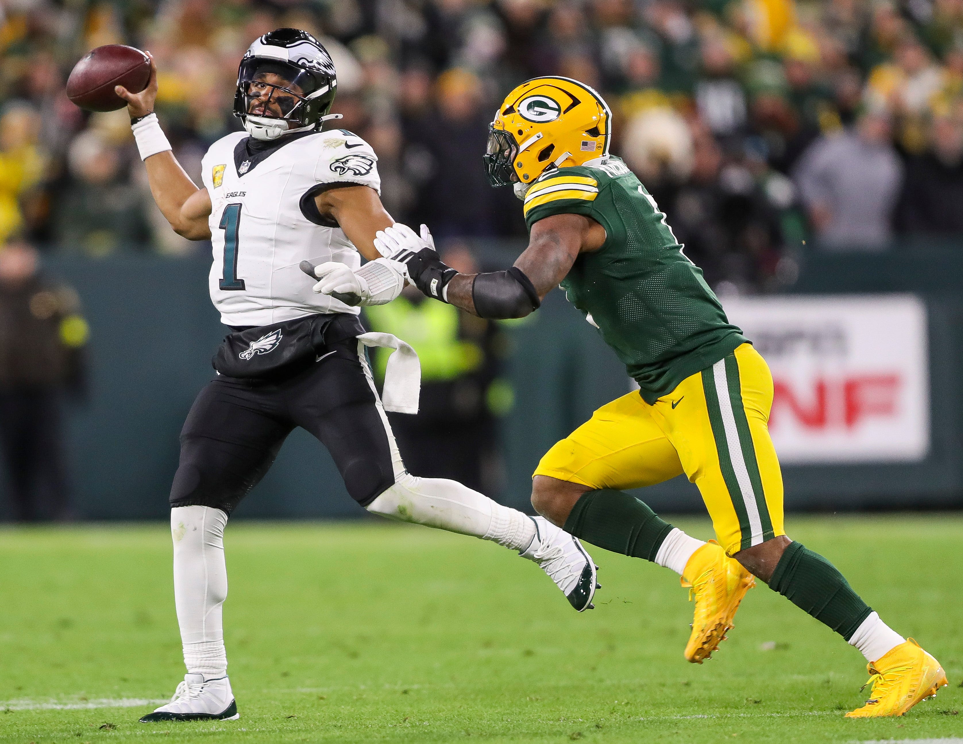 Philadelphia Eagles quarterback Jalen Hurts (1) throws on the run as Green Bay Packers defensive end Micah Parsons closes in on Monday, November 10, 2025, at Lambeau Field in Green Bay, Wis.