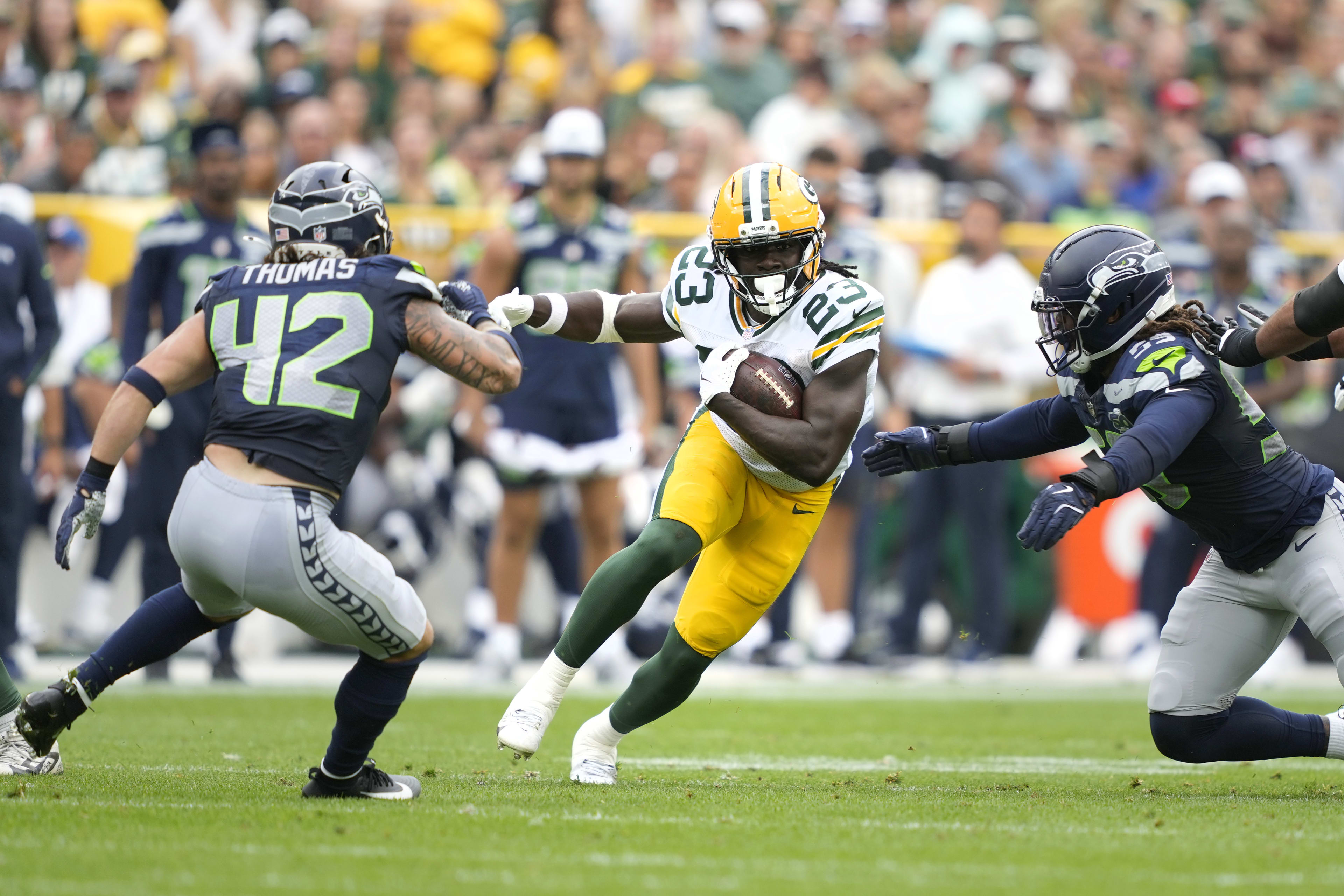 Aug 23, 2025; Green Bay, Wisconsin, USA; Green Bay Packers running back Israel Abanikanda (23) runs the ball against Seattle Seahawks linebacker Drake Thomas (42) and Seattle Seahawks linebacker Tyreke Smith (59) during the first half at Lambeau Field.