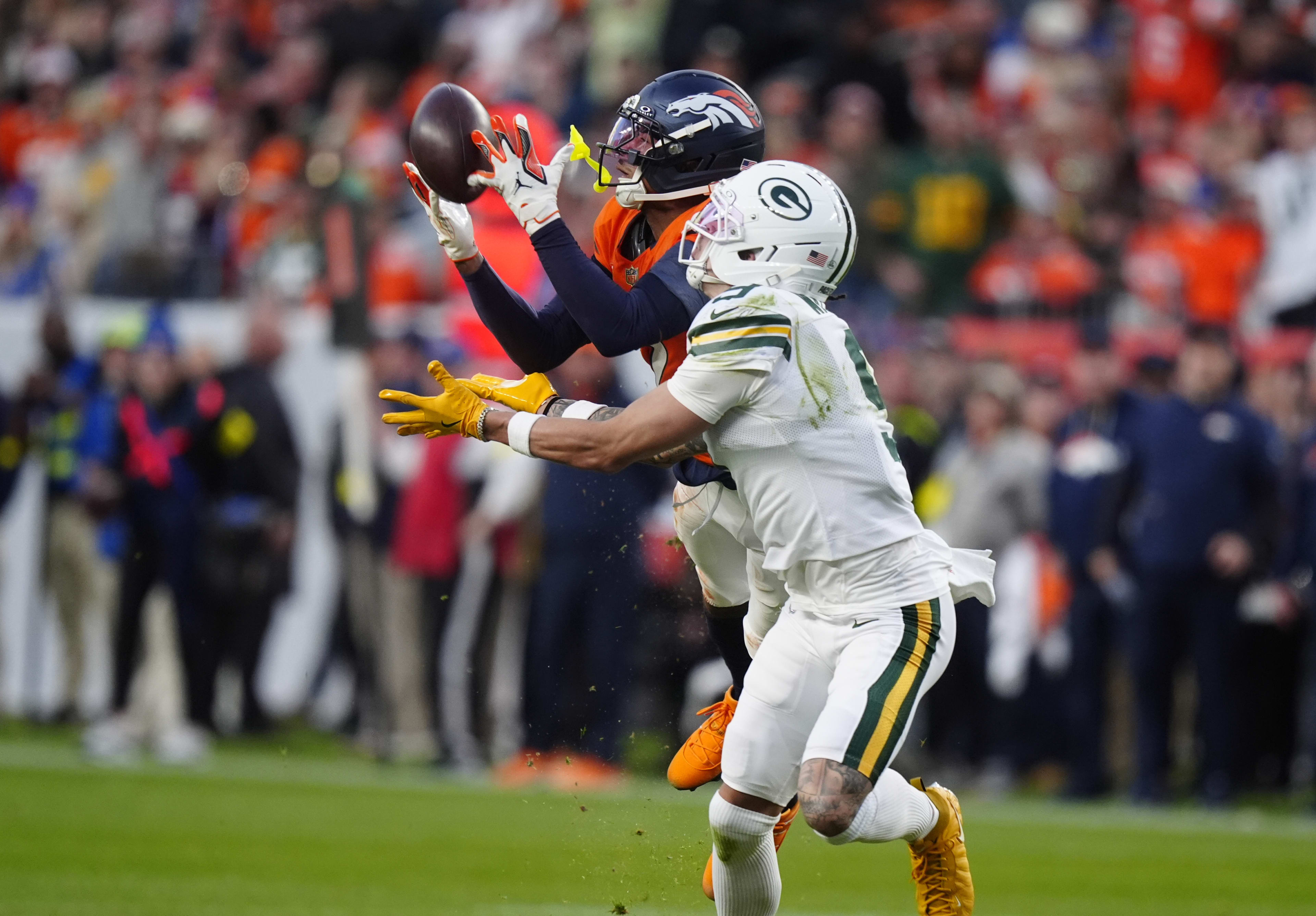 Dec 14, 2025; Denver, Colorado, USA; Denver Broncos cornerback Pat Surtain II (2) catches a pass under pressure from Green Bay Packers wide receiver Christian Watson (9) during the third quarter at Empower Field at Mile High.