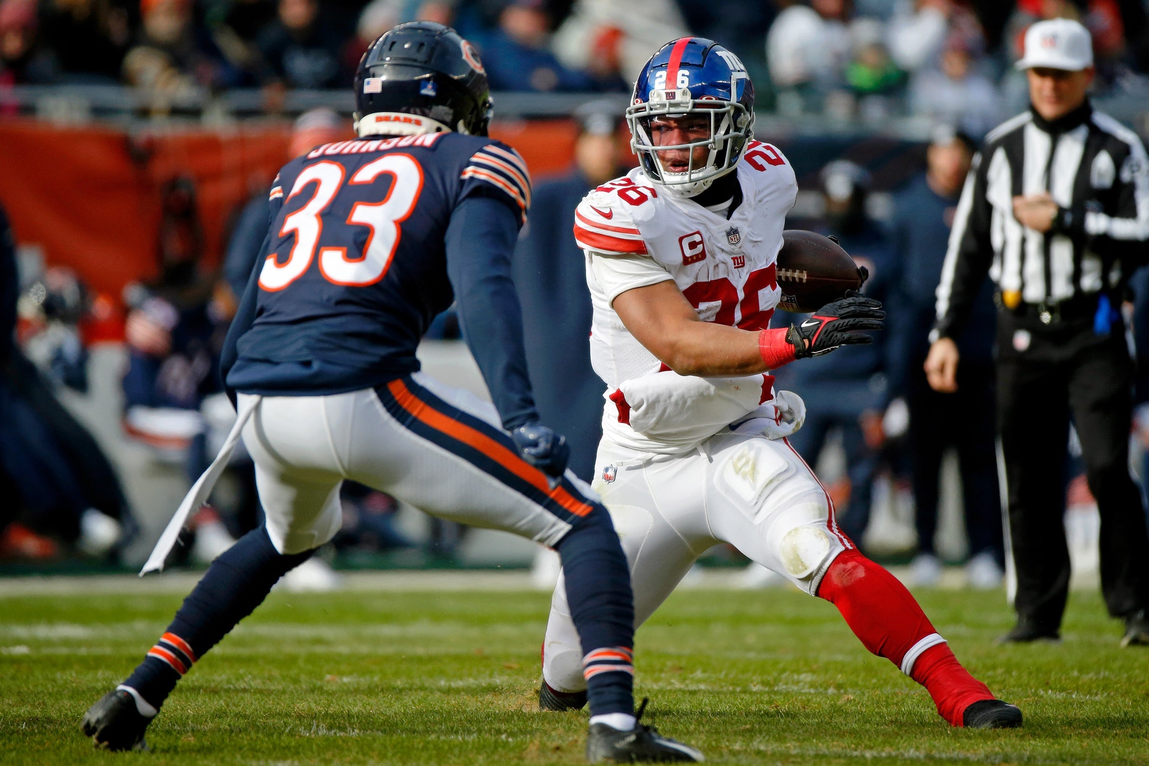 Jan 2, 2022; Chicago, Illinois, USA; New York Giants running back Saquon Barkley (26) runs with the ball against Chicago Bears cornerback Jaylon Johnson (33) during the first half at Soldier Field. Mandatory Credit: Jon Durr-USA TODAY Sports
