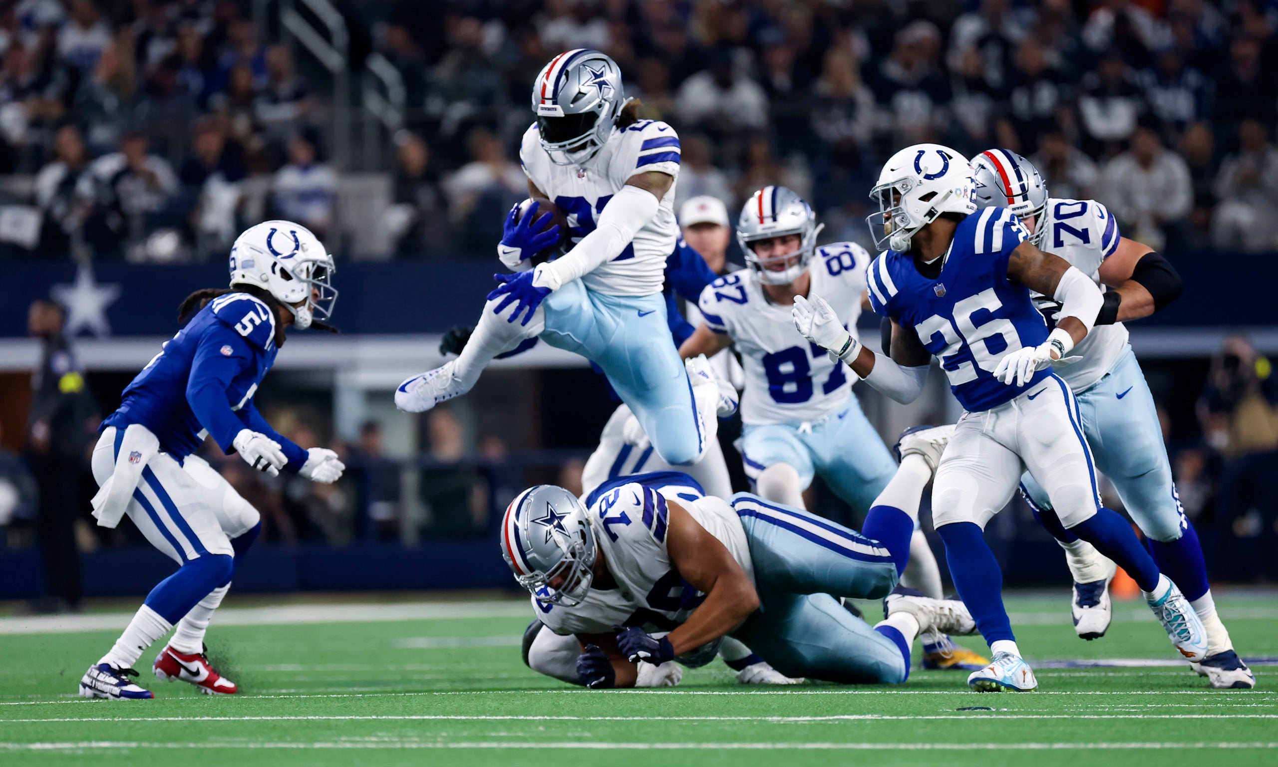 Dec 4, 2022; Arlington, Texas, USA;  Dallas Cowboys running back Ezekiel Elliott (21) hurdles Indianapolis Colts defensive tackle DeForest Buckner (99) during the first quarter at AT&T Stadium. Mandatory Credit: Kevin Jairaj-USA TODAY Sports
