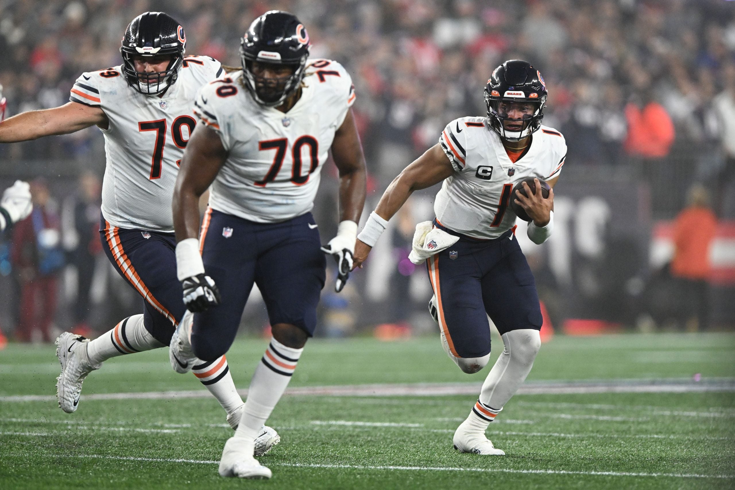 Oct 24, 2022; Foxborough, Massachusetts, USA; Chicago Bears quarterback Justin Fields (1) runs with the ball with guard Michael Schofield III (79) and Chicago Bears offensive tackle Braxton Jones (70) during the first half of a game against the New England Patriots at Gillette Stadium. Mandatory Credit: Brian Fluharty-USA TODAY Sports