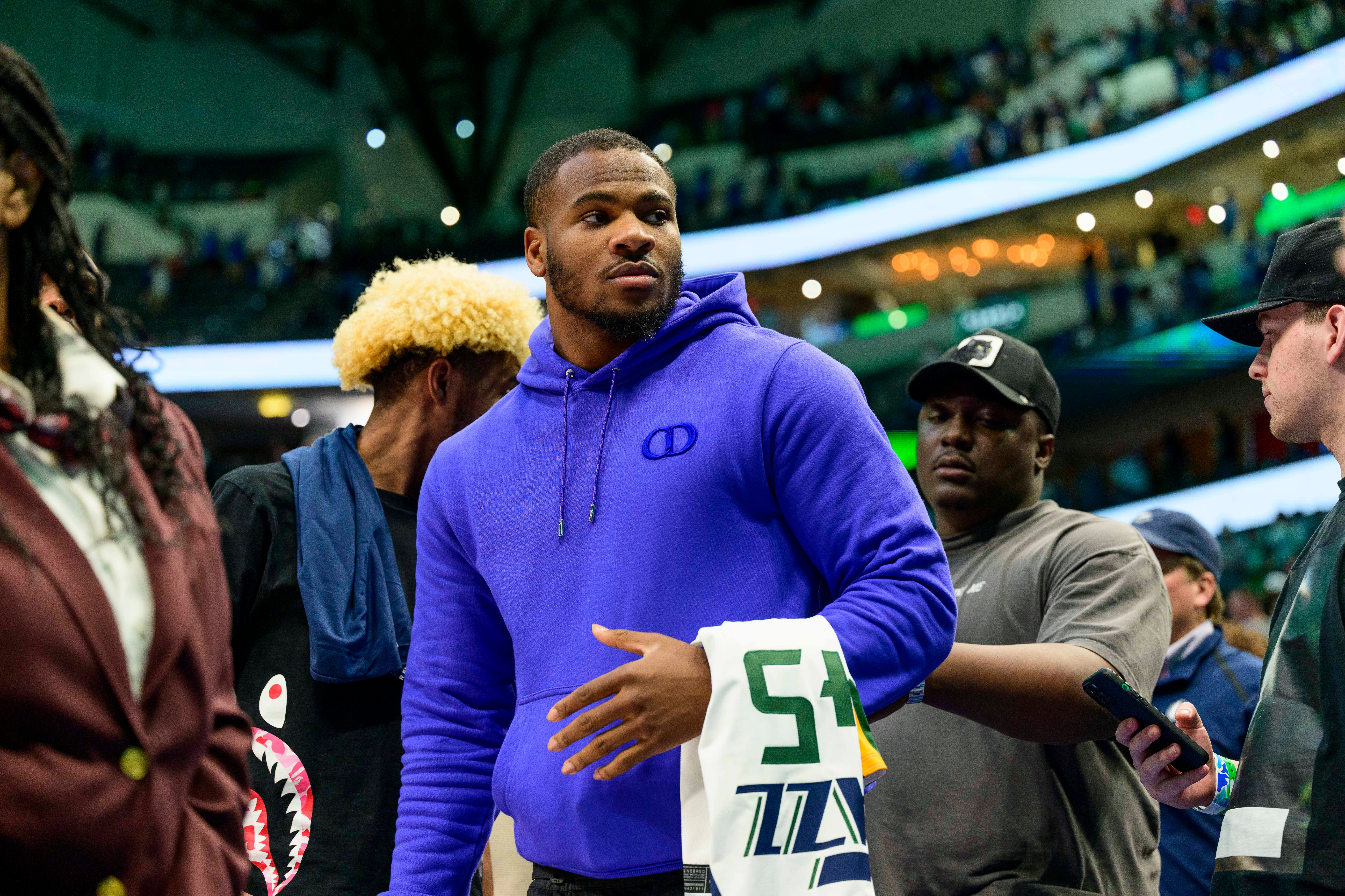 Mar 27, 2022; Dallas, Texas, USA; Dallas Cowboys linebacker Micah Parsons walks off the court with the jersey of Utah Jazz guard Donovan Mitchell (45) after the game against the Dallas Mavericks at the American Airlines Center. Mandatory Credit: Jerome Miron-USA TODAY Sports
