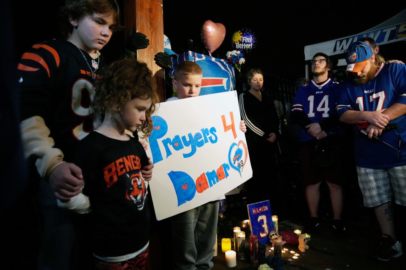 Brody Bennett, 13, left, stands with his sister Cameron Wilburn, 6, and brother, Tatem Wilburn 8, of Bellevue, Ky. as football fans pause for a moment of silence during a vigil for Buffalo Bills safety Damar Hamlin Tuesday, January 3, 2023. The vigil was held outside of the University of Cincinnati Medical Center at 8:55 p.m., 24 hours after Hamlin collapsed during the Monday Night Football game with the Bengals. Hamilin remains in critical condition at the UC Medical Center. Vigil3
