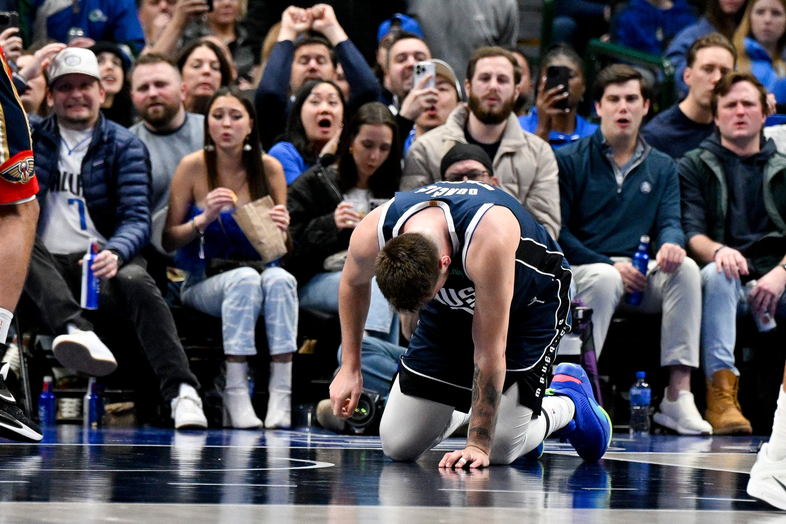 Luka Doncic kneels on the ground after injuring his heel against the Pelicans.