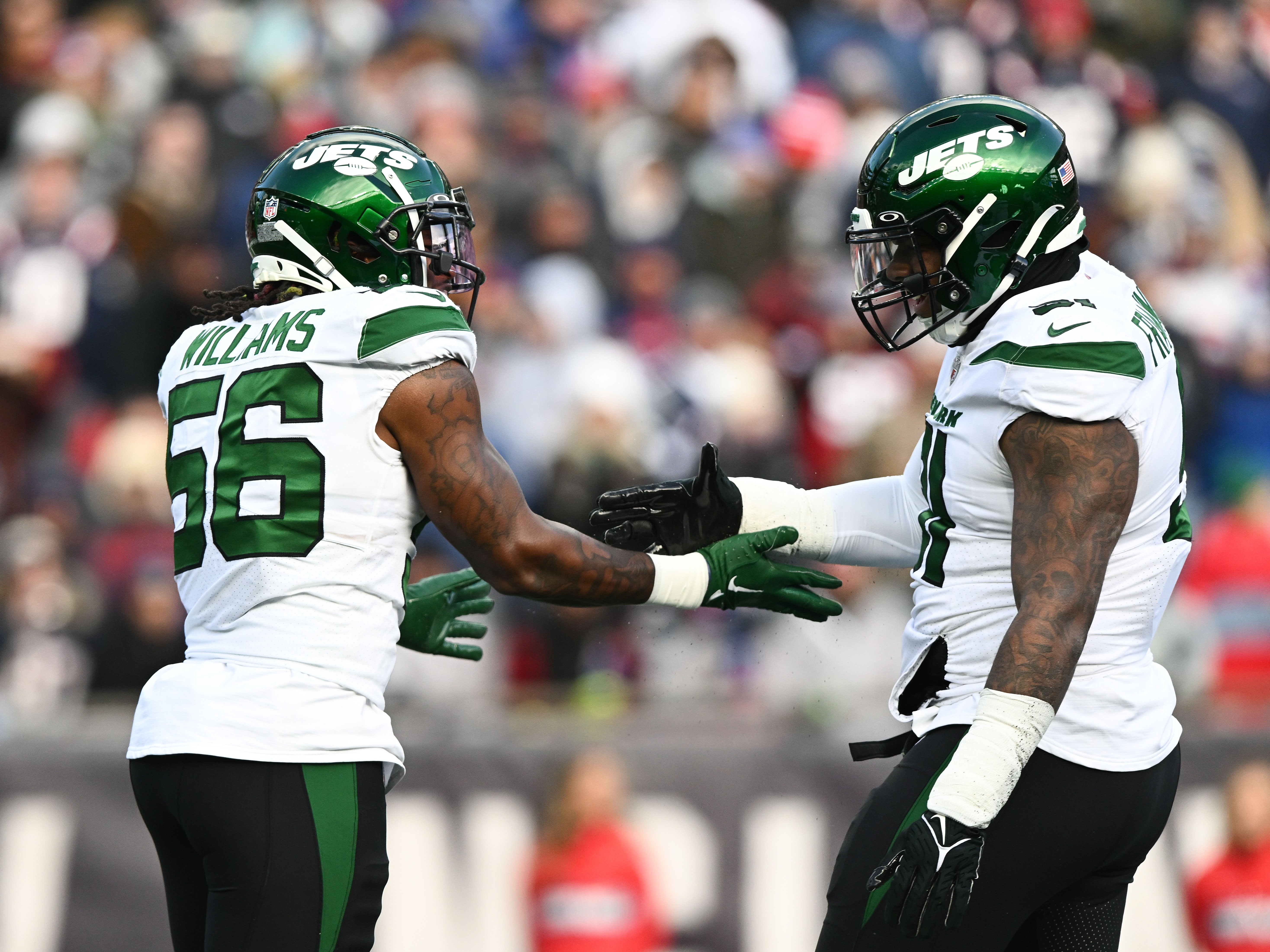 New York Jets linebacker Quincy Williams (56) celebrates with defensive end John Franklin-Myers (91) after sacking New England Patriots quarterback Mac Jones (not seen) during the first half at Gillette Stadium.