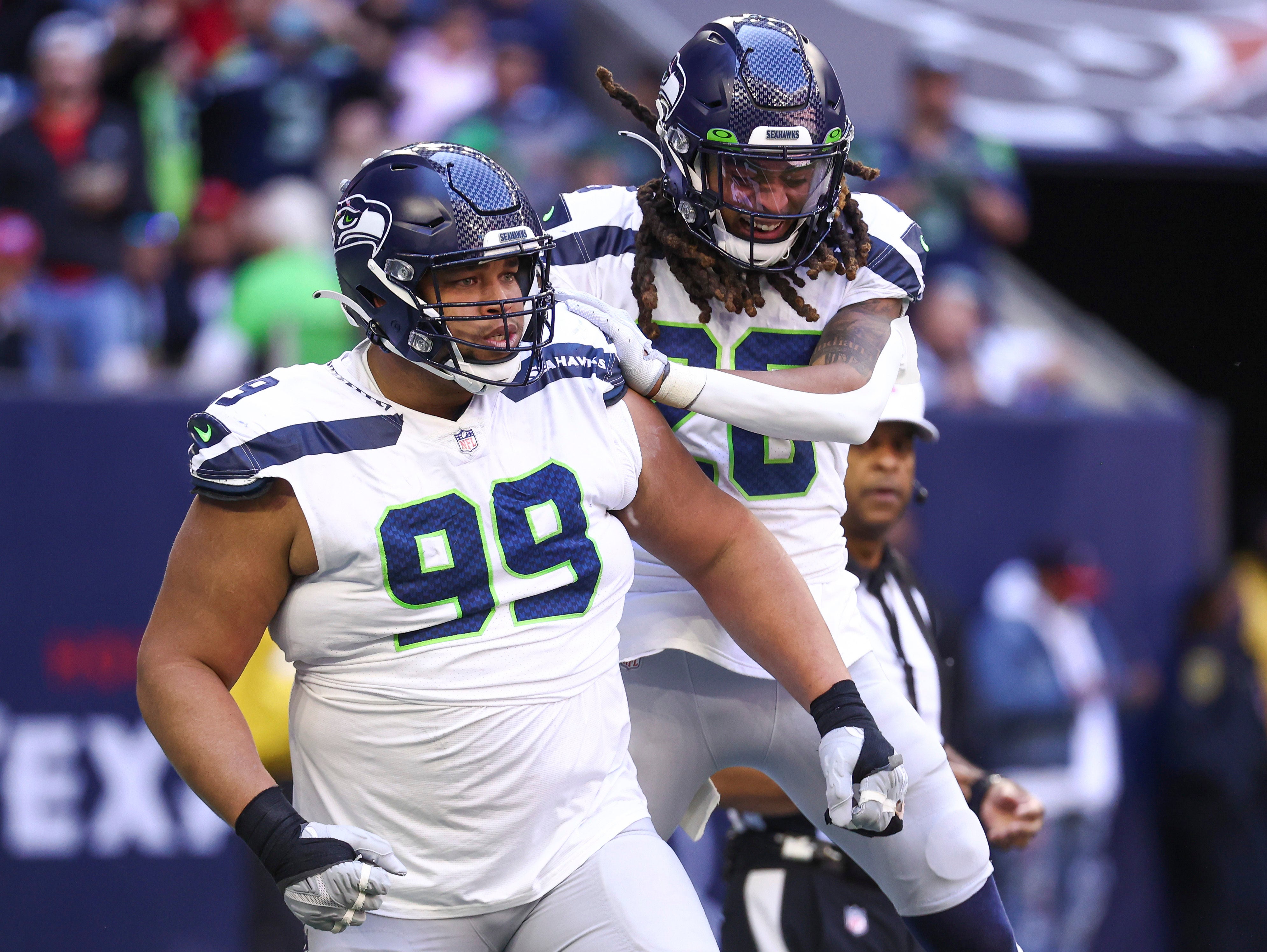 Dec 12, 2021; Houston, Texas, USA; Seattle Seahawks defensive back Ryan Neal (26) celebrates with defensive tackle Al Woods (99) after a defensive play during the second quarter against the Houston Texans at NRG Stadium.