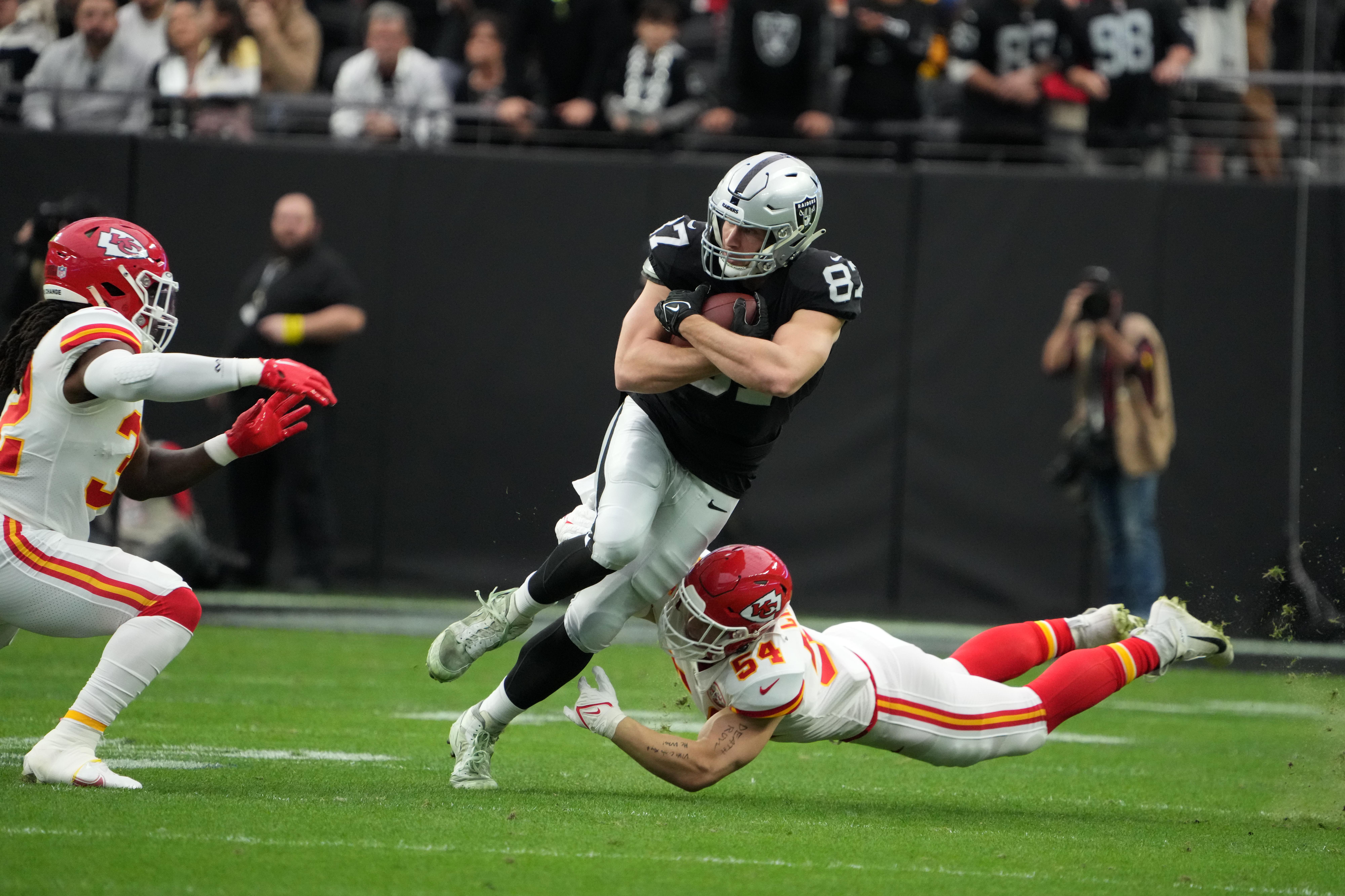 Jan 7, 2023; Paradise, Nevada, USA; Las Vegas Raiders tight end Foster Moreau (87) carries the ball against Kansas City Chiefs linebackers Nick Bolton (32) and Leo Chenal (54) in the first half at Allegiant Stadium.