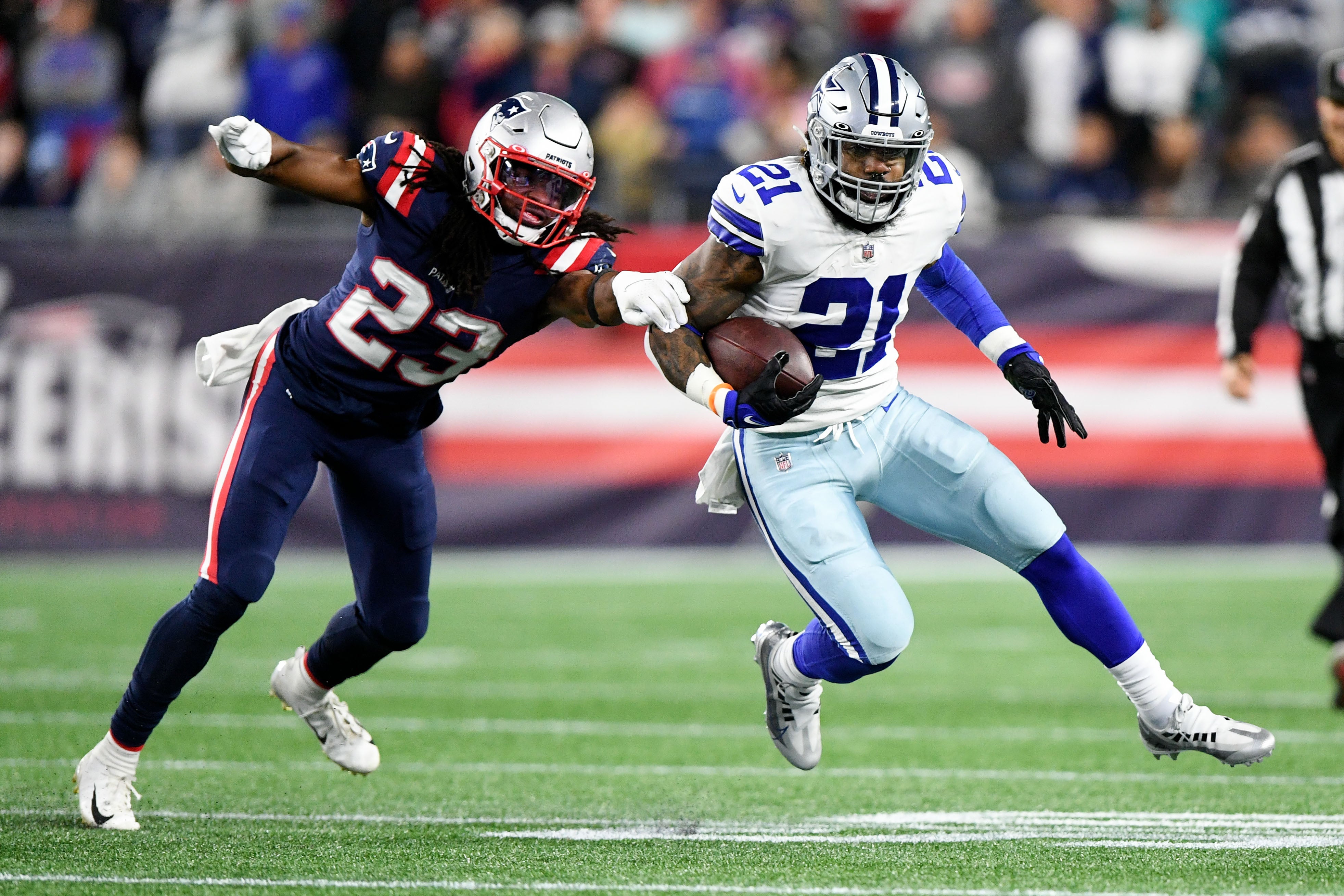 Oct 17, 2021; Foxborough, Massachusetts, USA; Dallas Cowboys running back Ezekiel Elliott (21) breaks a tackle from New England Patriots defensive back Kyle Dugger (23) during the second half at Gillette Stadium.