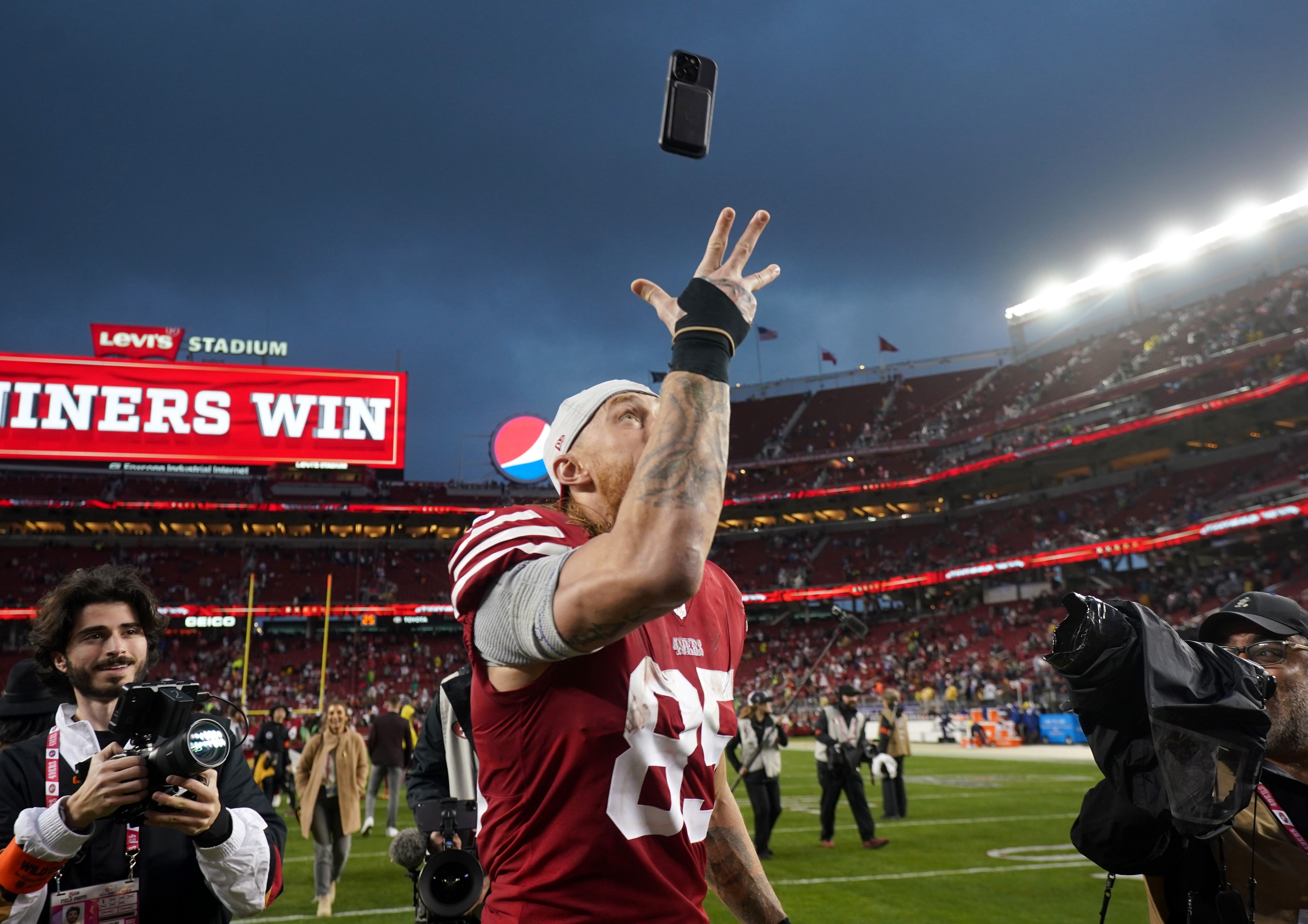 Jan 14, 2023; Santa Clara, California, USA; San Francisco 49ers tight end George Kittle (85) tosses a cell phone as he walks off the field after defeating the Seattle Seahawks in a wild card game at Levi's Stadium.