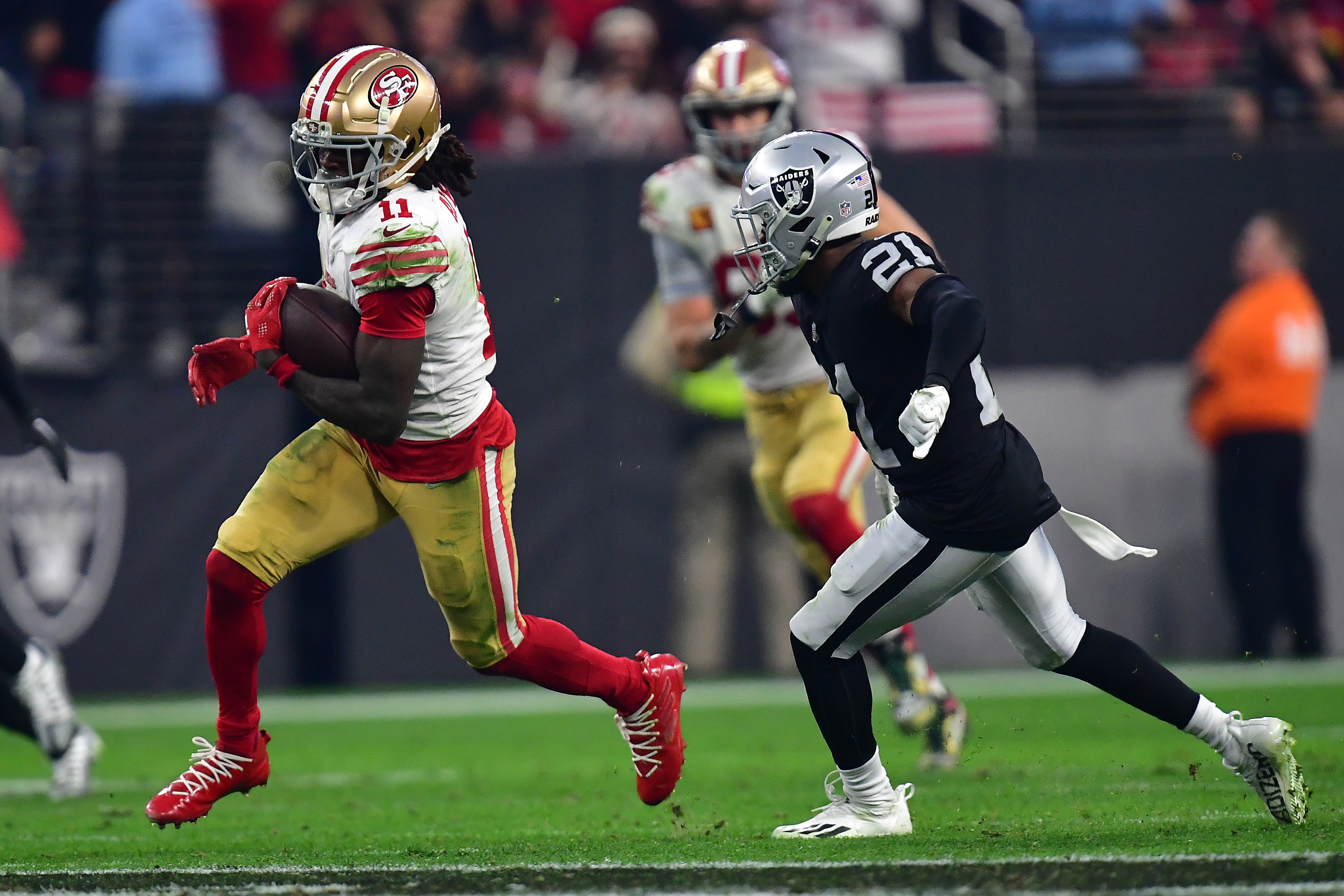 January 1, 2023; Paradise, Nevada, USA; San Francisco 49ers wide receiver Brandon Aiyuk (11) runs the ball ahead of Las Vegas Raiders cornerback Amik Robertson (21) during the second half at Allegiant Stadium. Mandatory Credit: Gary A. Vasquez-USA TODAY Sports