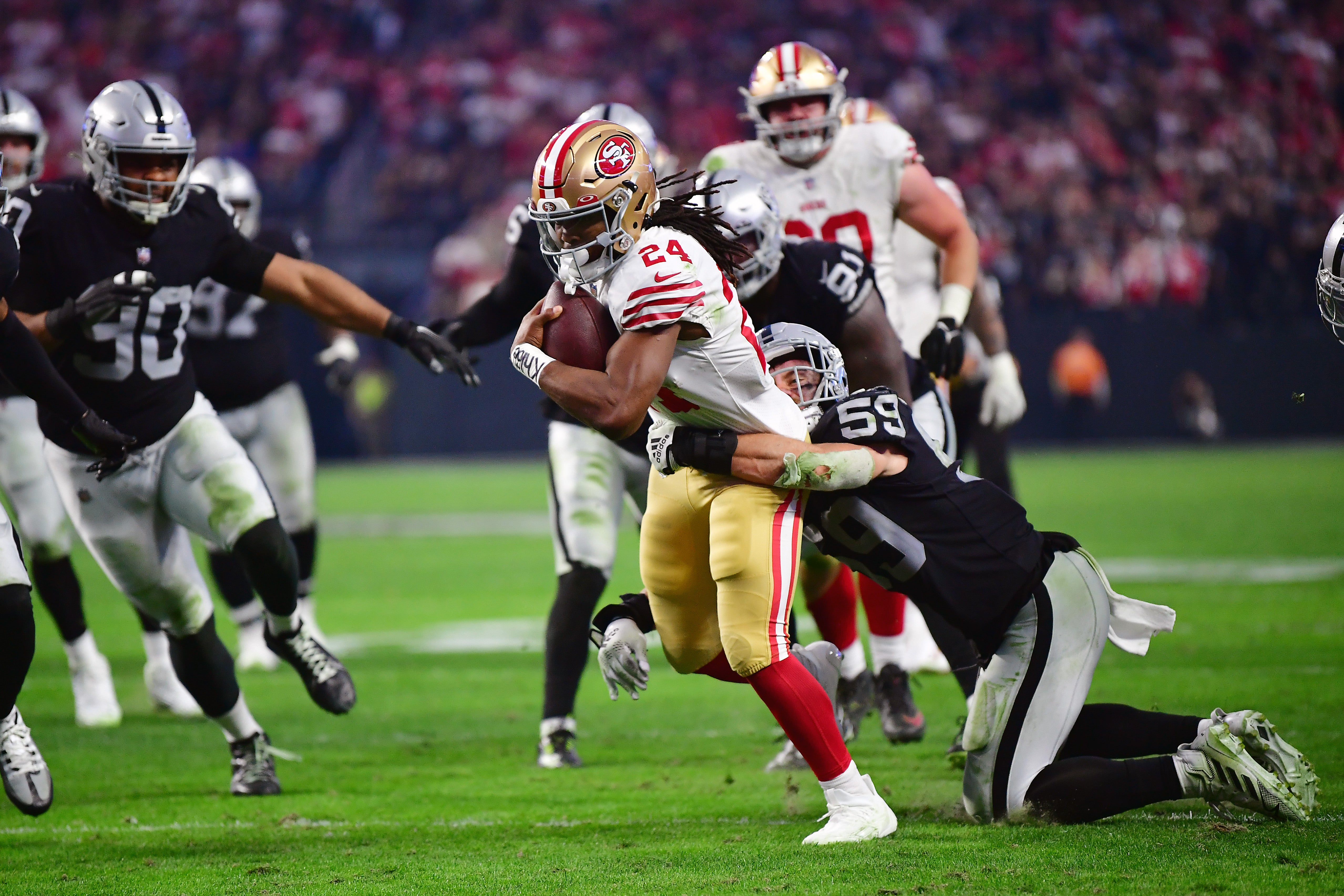January 1, 2023; Paradise, Nevada, USA; San Francisco 49ers running back Jordan Mason (24) runs the ball against Las Vegas Raiders linebacker Luke Masterson (59) during the second half at Allegiant Stadium. Mandatory Credit: Gary A. Vasquez-USA TODAY Sports