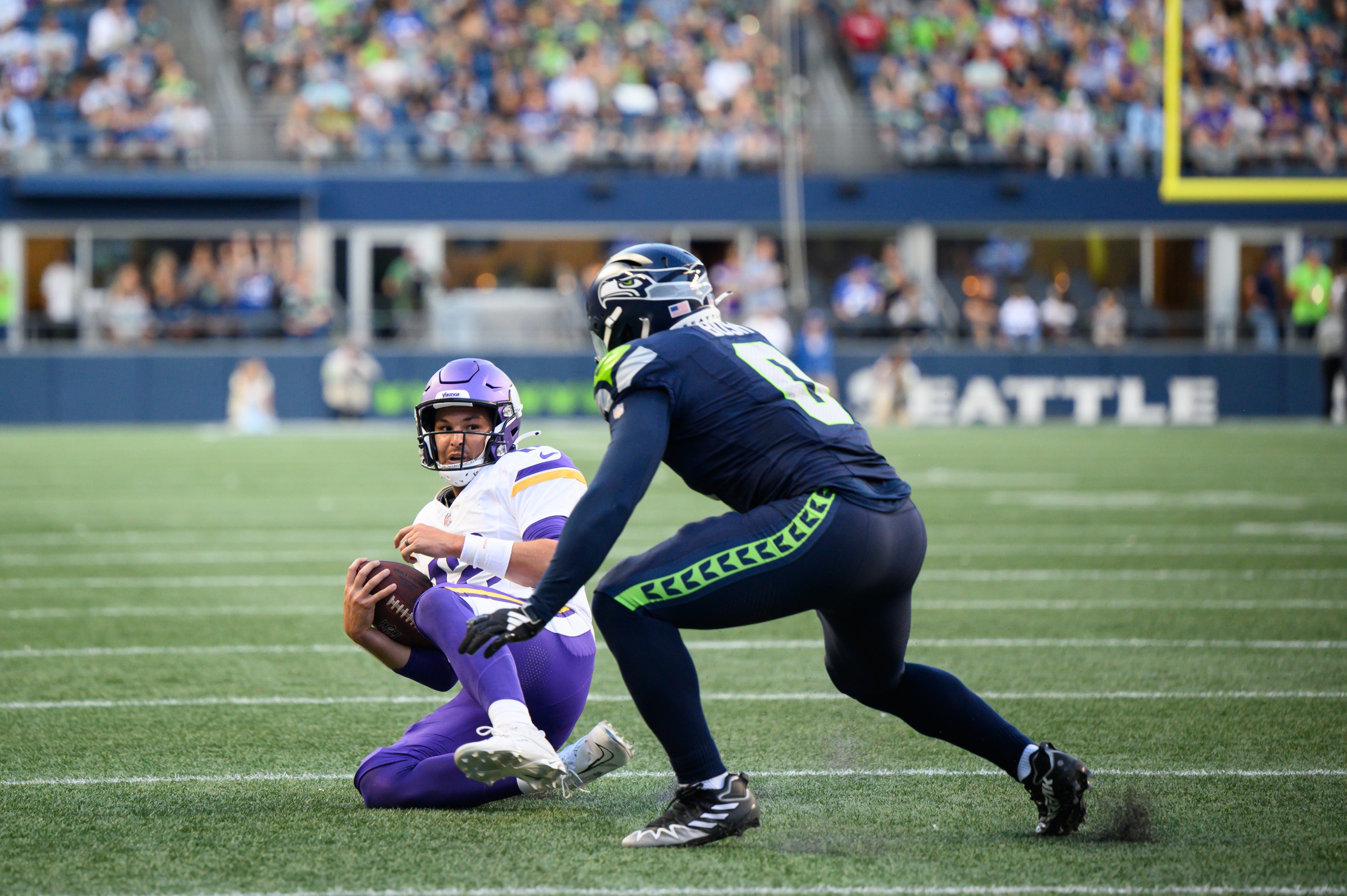 Aug 10, 2023; Seattle, Washington, USA; Minnesota Vikings quarterback Nick Mullens (12) slides in front of Seattle Seahawks linebacker Devin Bush (0) during the first half at Lumen Field. Mandatory Credit: Steven Bisig-USA TODAY Sports