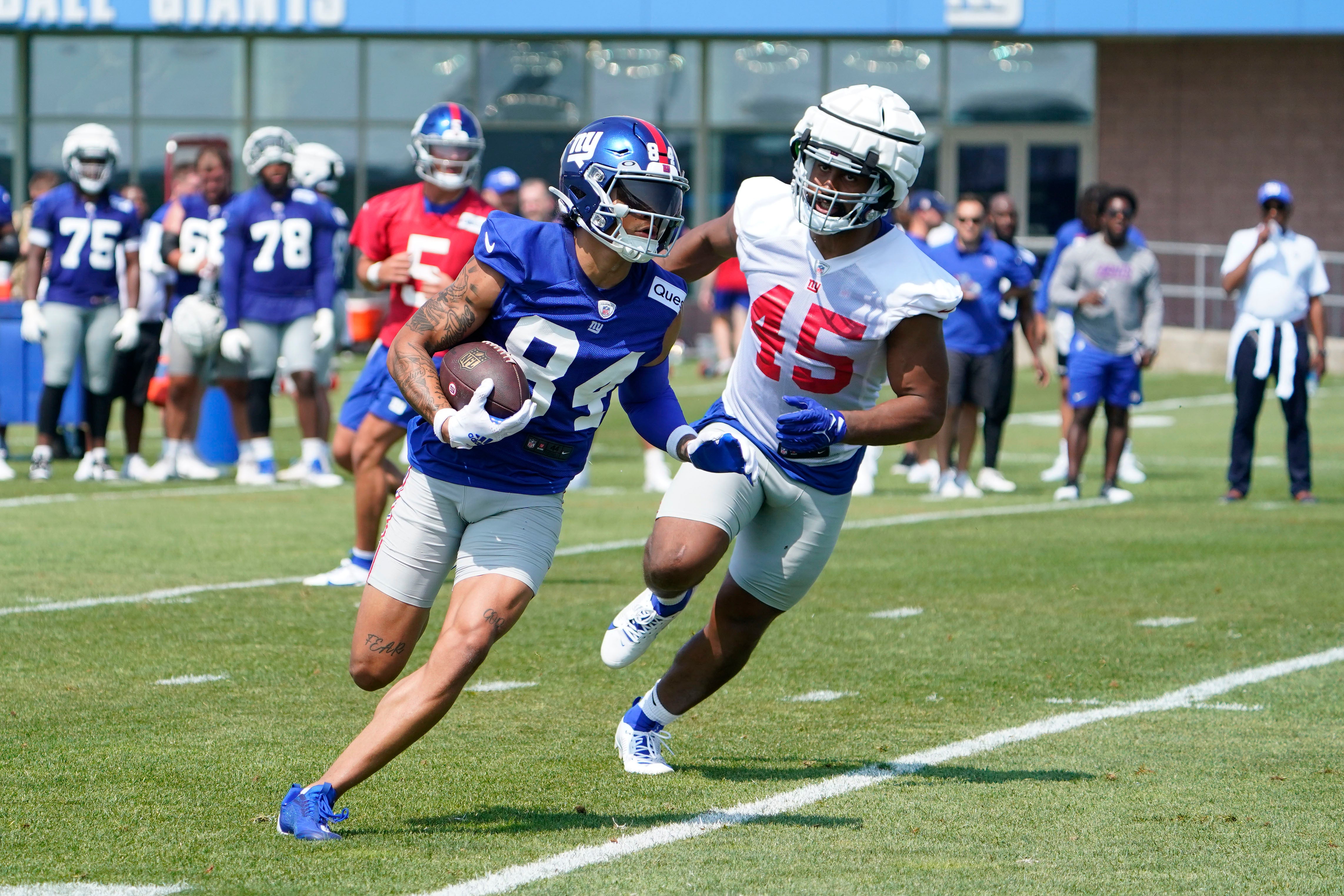 Jul 26, 2023; East Rutherford, NJ, USA; New York Giants rookie wide receiver Jalin Hyatt (84) runs with the ball with pressure from rookie linebacker Habakkuk Baldonado (45) on the first day of training camp at the Quest Diagnostics Training Facility. Mandatory Credit: Danielle Parhizkaran-USA TODAY Sports
