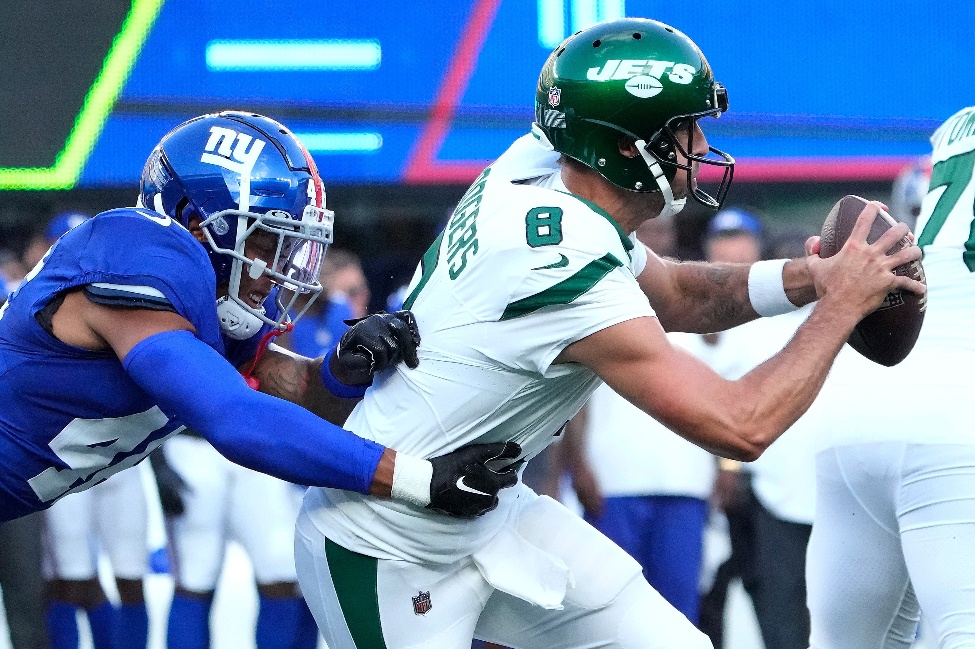 Aug 26, 2023; East Rutherford, New Jersey, USA; New York Jets quarterback Aaron Rodgers (8) pressured by New York Giants inside linebacker Isaiah Simmons (left) during the first half at MetLife Stadium. Mandatory Credit: Robert Deutsch-USA TODAY Sports