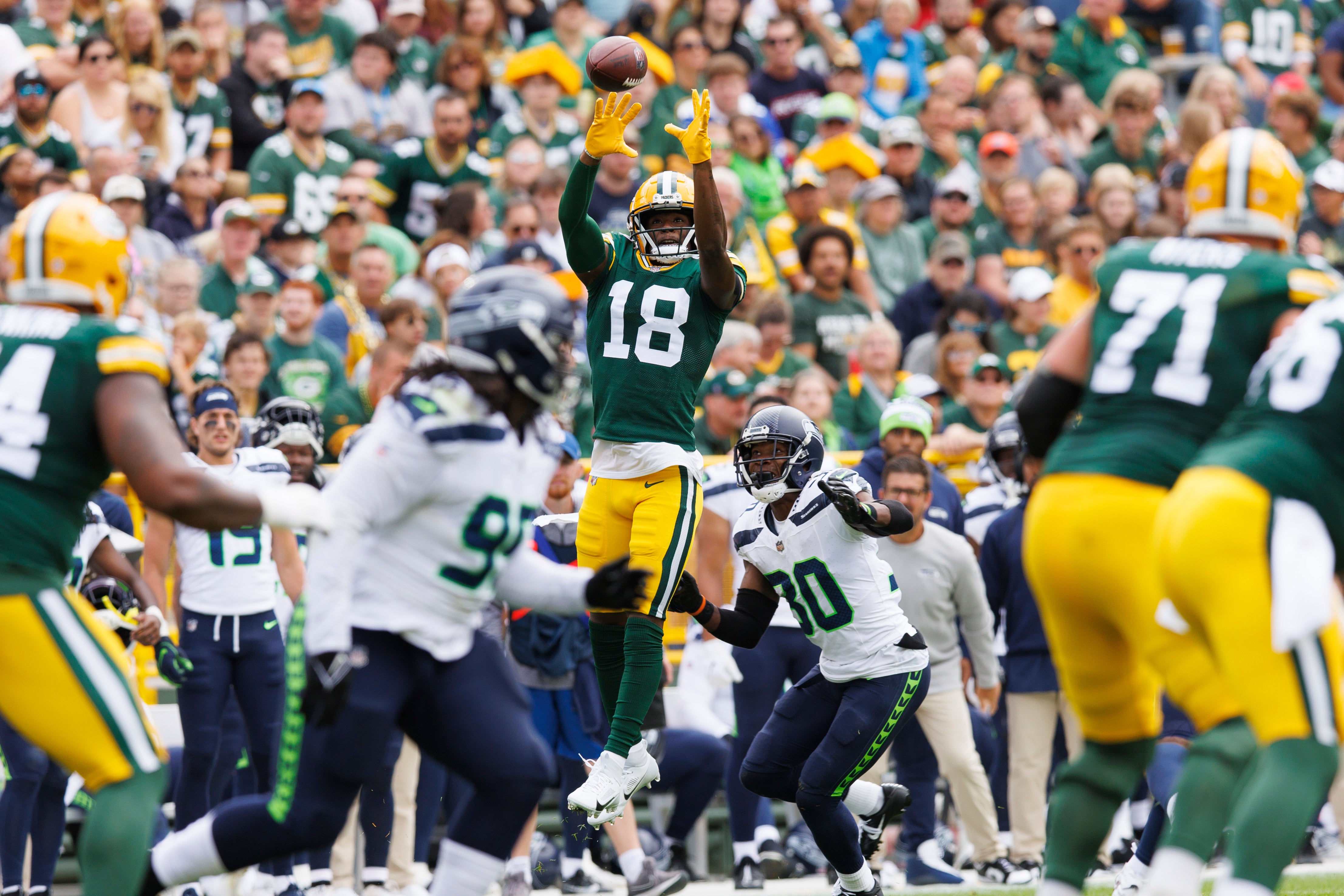 Aug 26, 2023; Green Bay, Wisconsin, USA; Green Bay Packers wide receiver Malik Heath (18) leaps to catch a pass in front of Seattle Seahawks cornerback Michael Jackson (30) during the first quarter at Lambeau Field. Jeff Hanisch-USA TODAY Sports